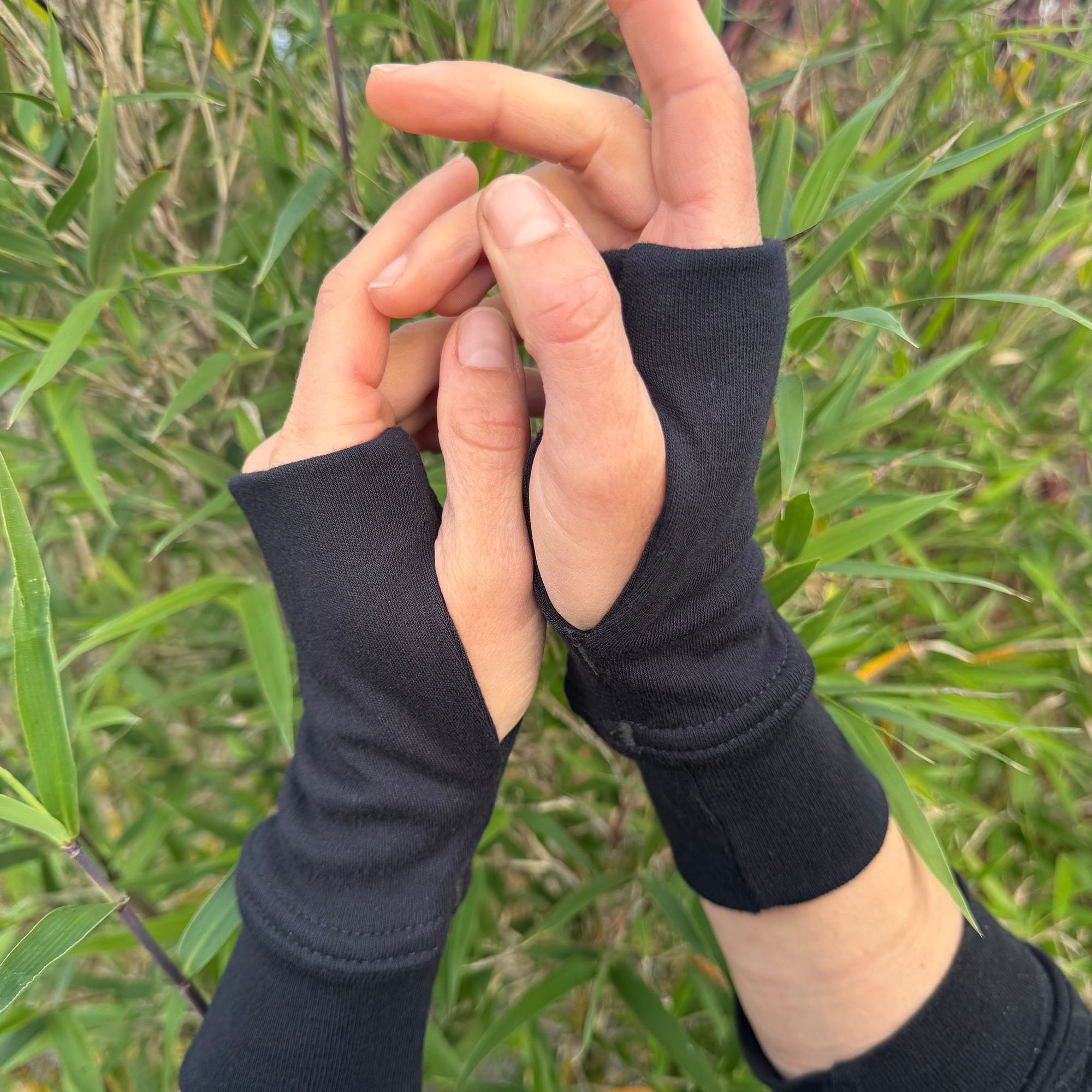 Organic cotton hand warmers, black fabric with natural background.