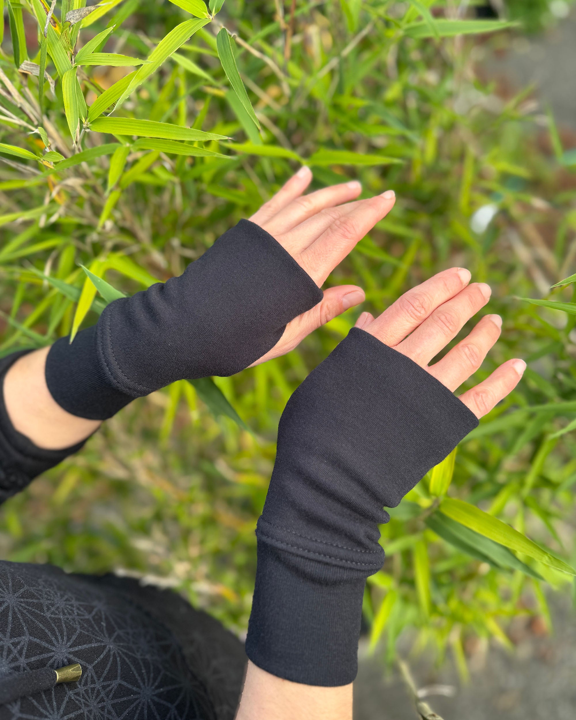 organic cotton hand warmers, black fabric with bamboo natural background.