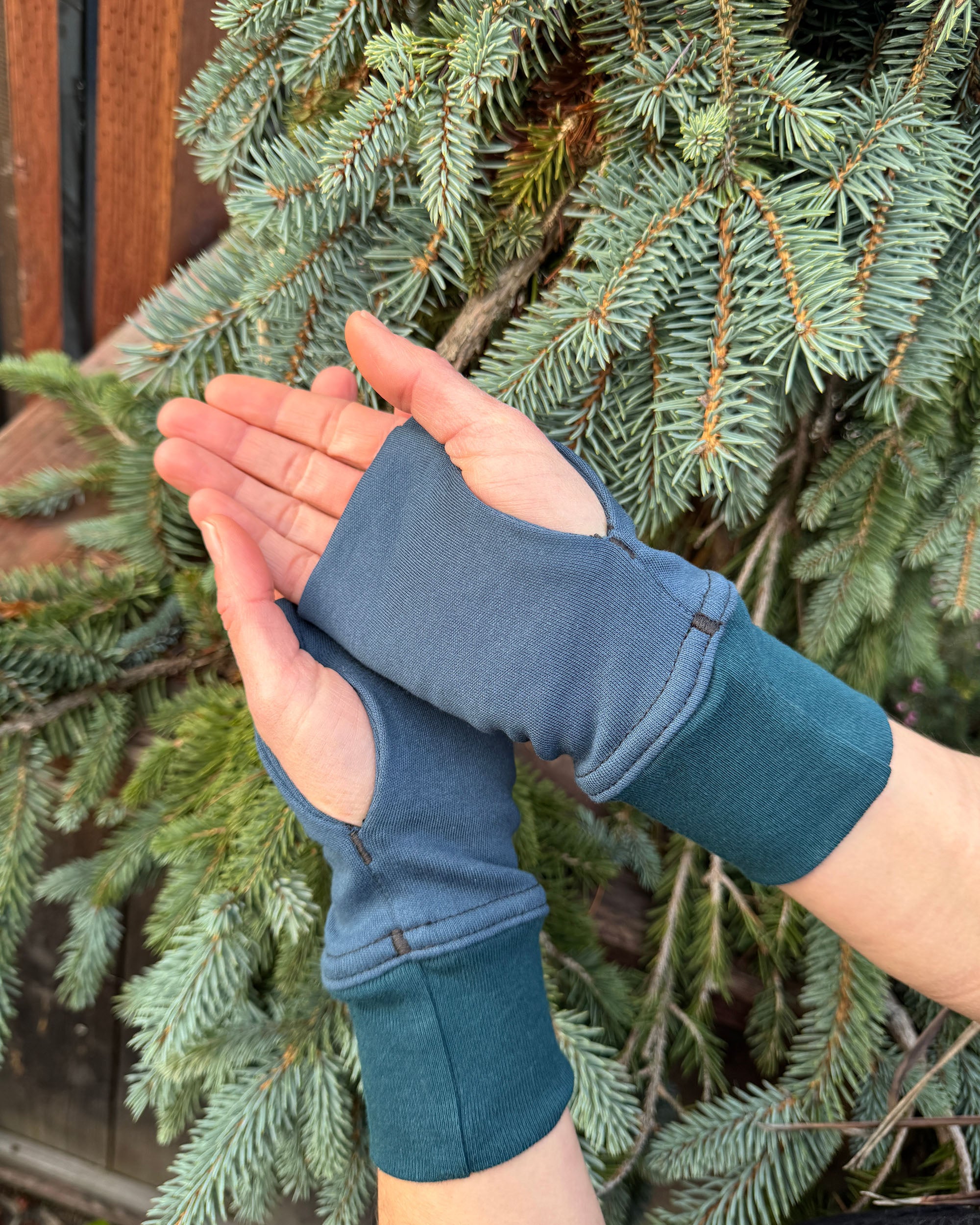 Female hands wearing dark blue organic cotton hand warmers.