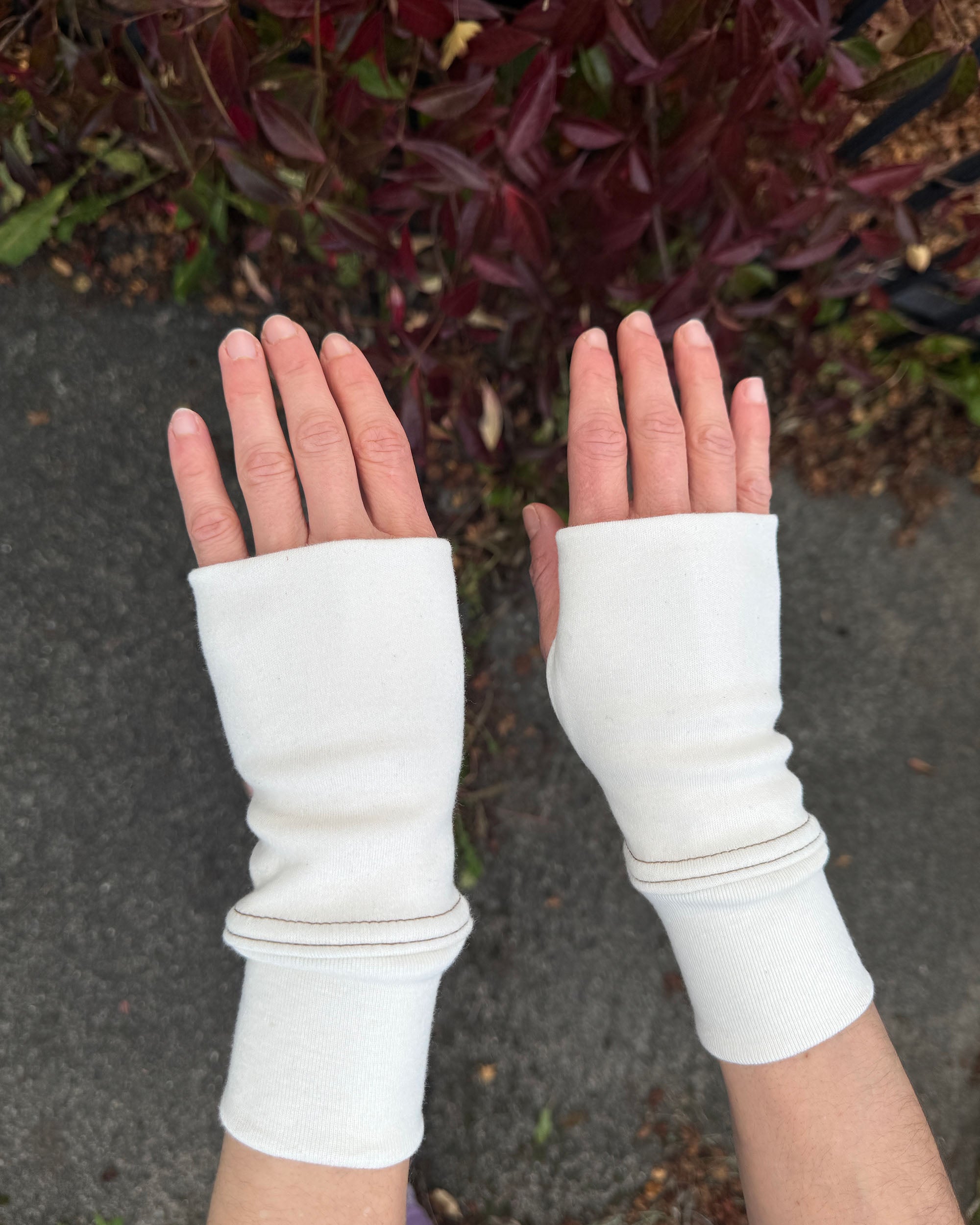 Female hands wearing organic cotton and un-dyed hand warmers.