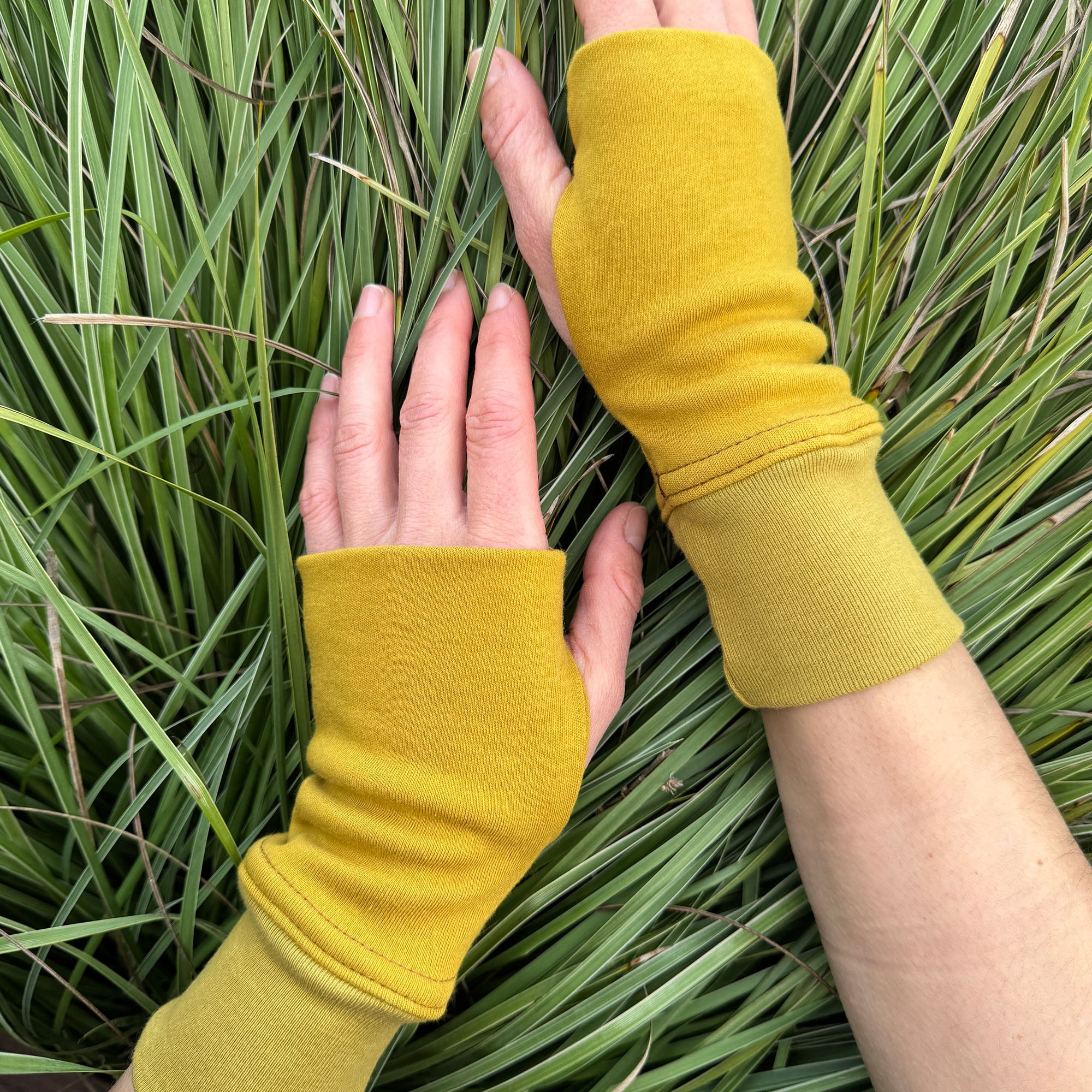 Organic cotton hand warmers, mustard solid fabric with grassy background.