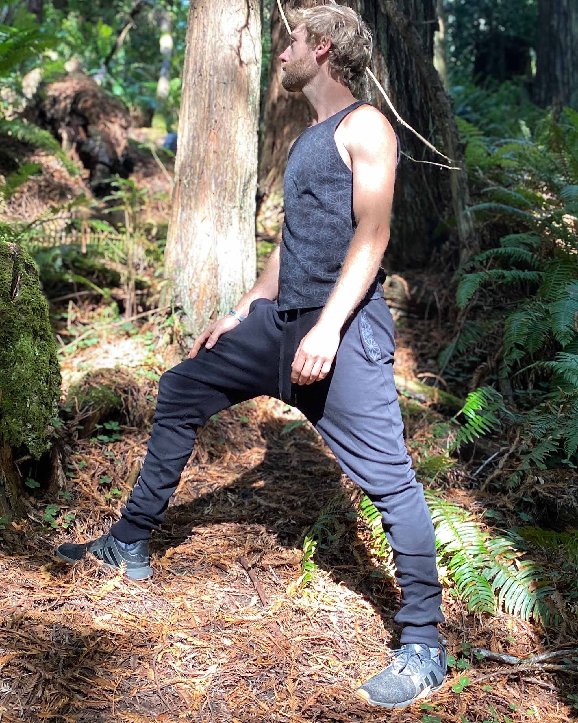 Organic cotton unisex joggers, black fabric, left side full body view on male model in nature.