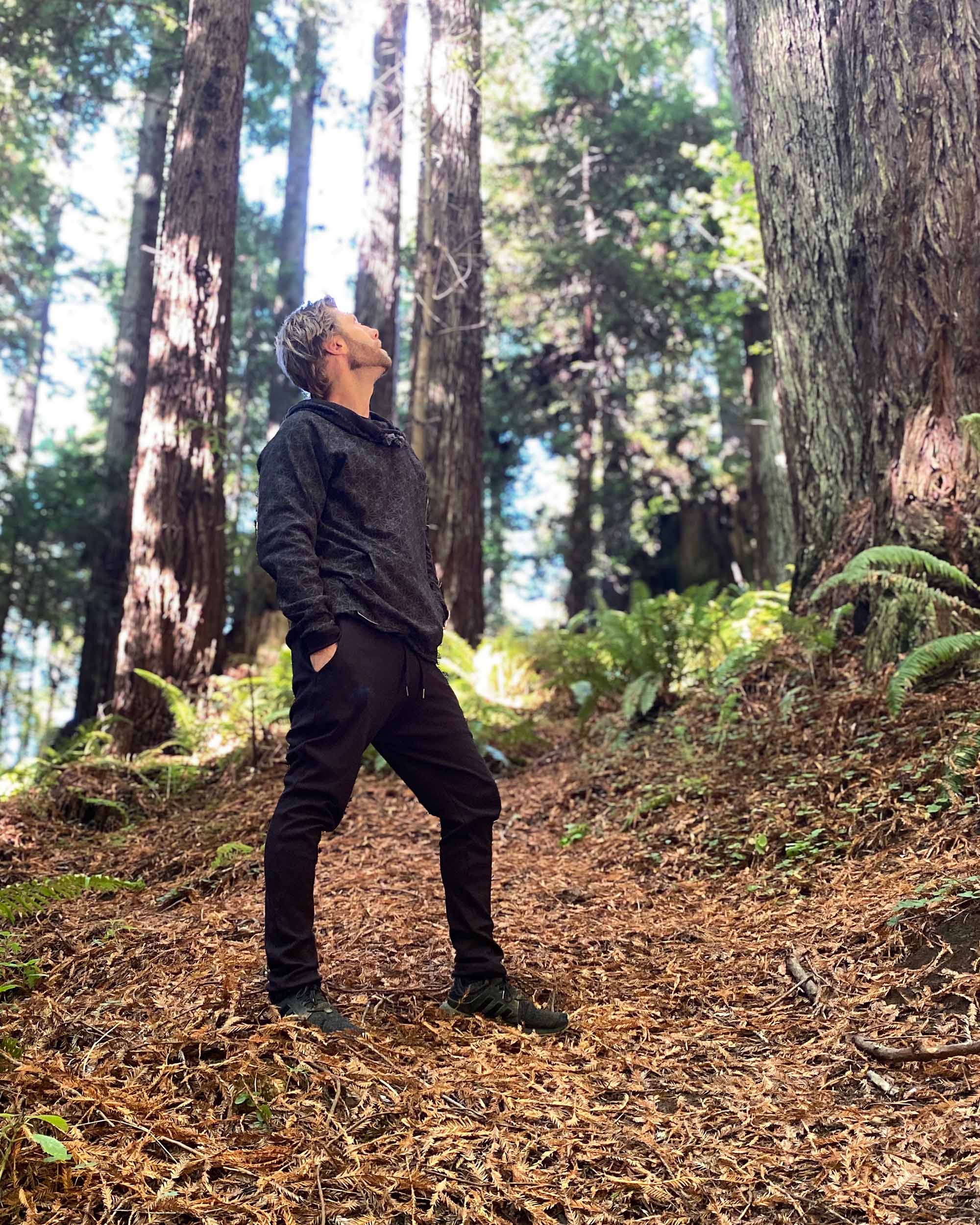 Organic cotton unisex joggers, black fabric, right side full body view on male model in nature.