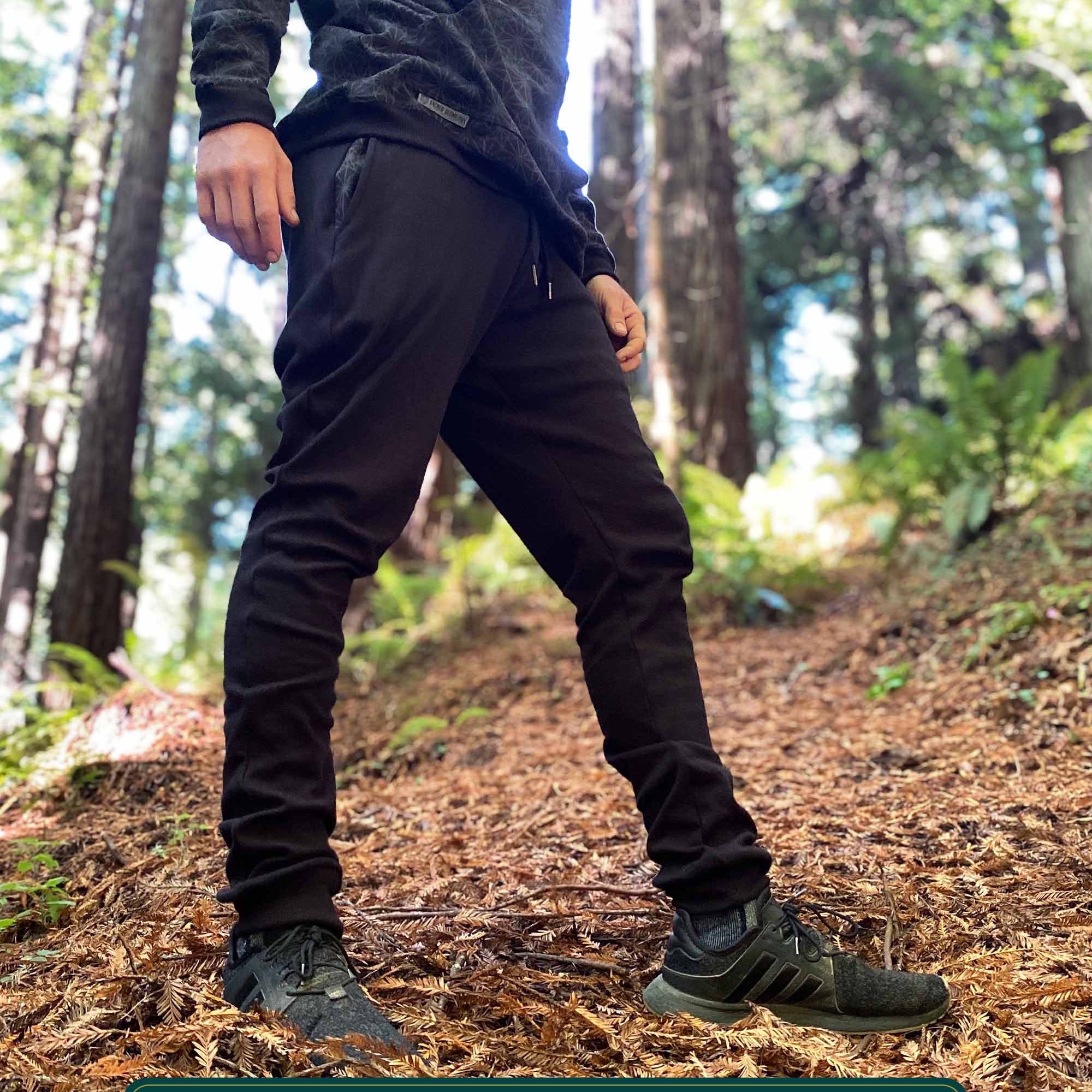 Organic cotton unisex joggers, black fabric, right side view on male model in nature.