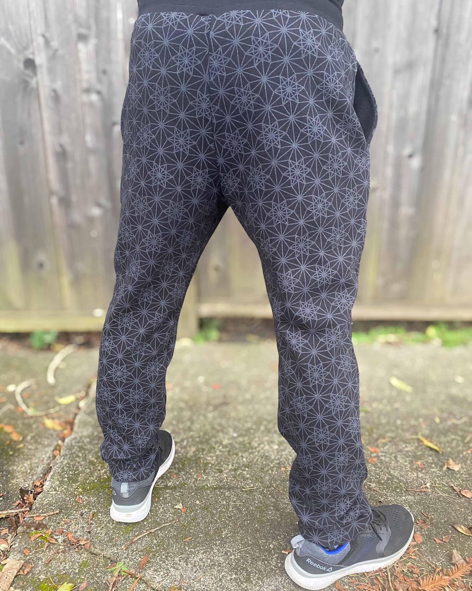 Organic cotton unisex joggers, black fabric with geometric print, back view on male model.