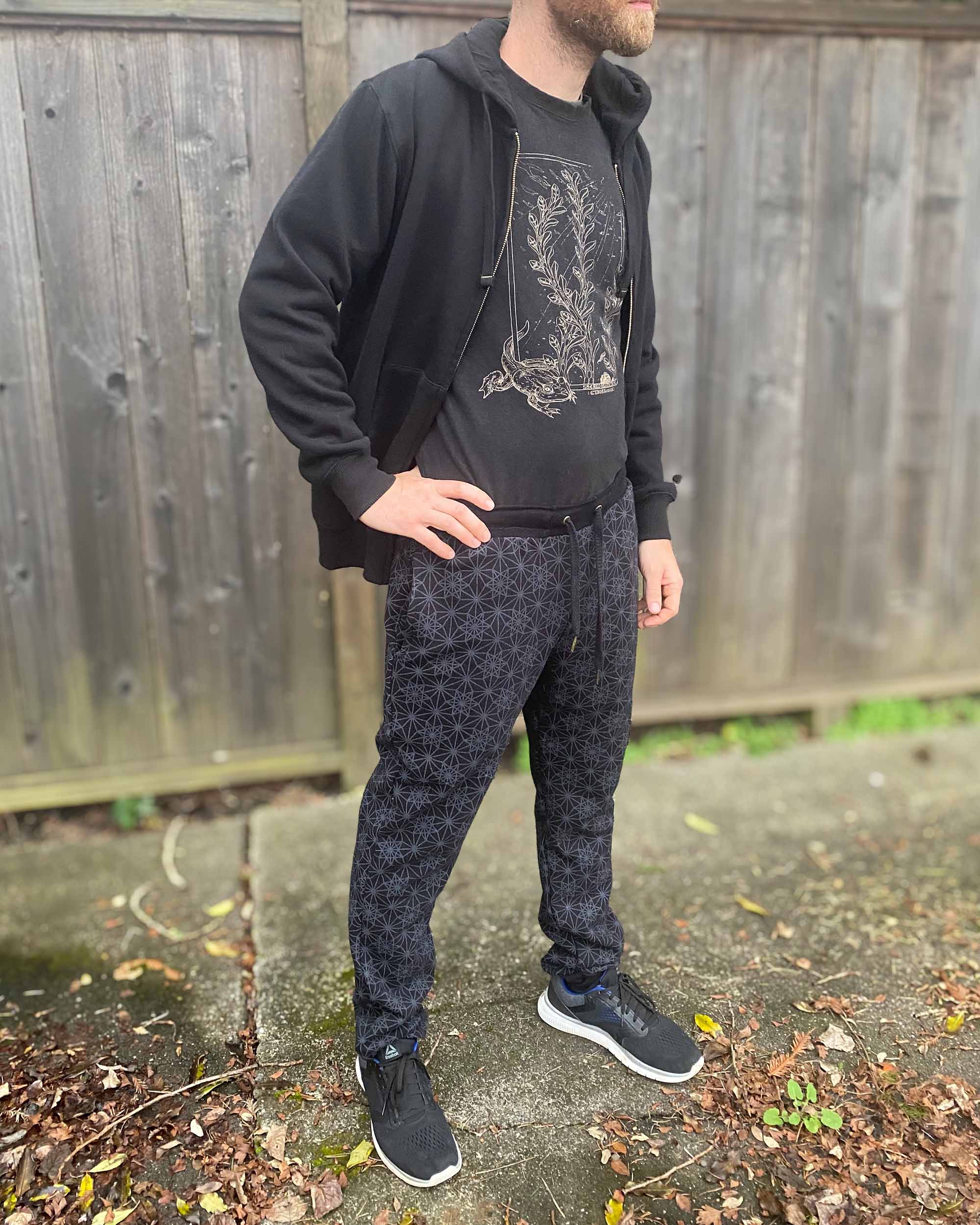 Organic cotton unisex joggers, black fabric with geometric print, front view on male model in natural lighting.