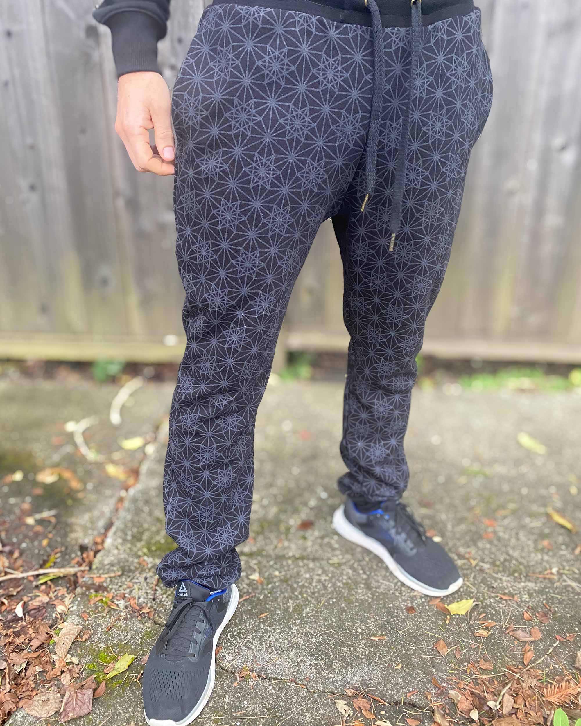 Organic cotton unisex joggers, black fabric with geometric print, right side view on male model.