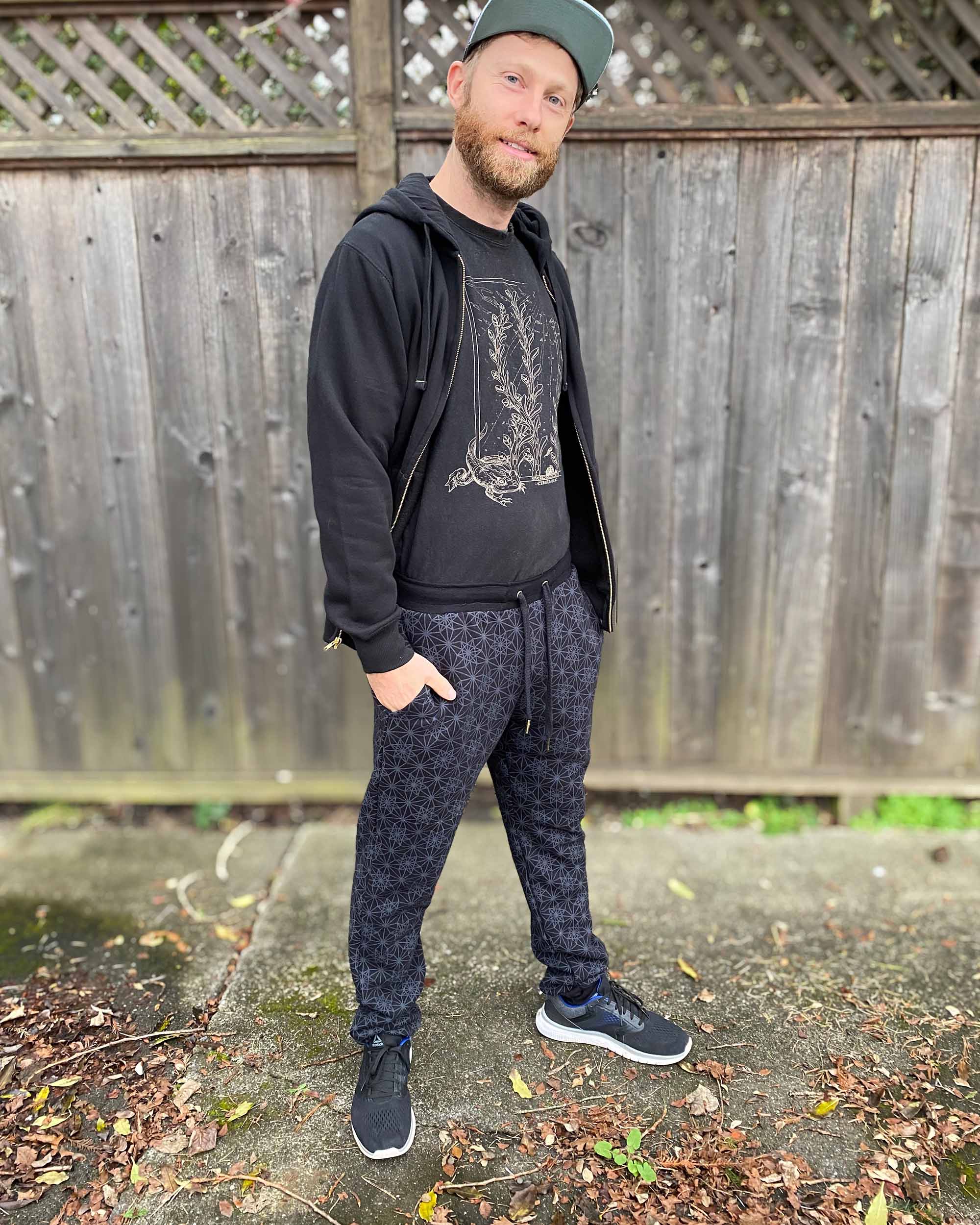 Organic cotton unisex joggers, black fabric with geometric print, full body front view on male model.