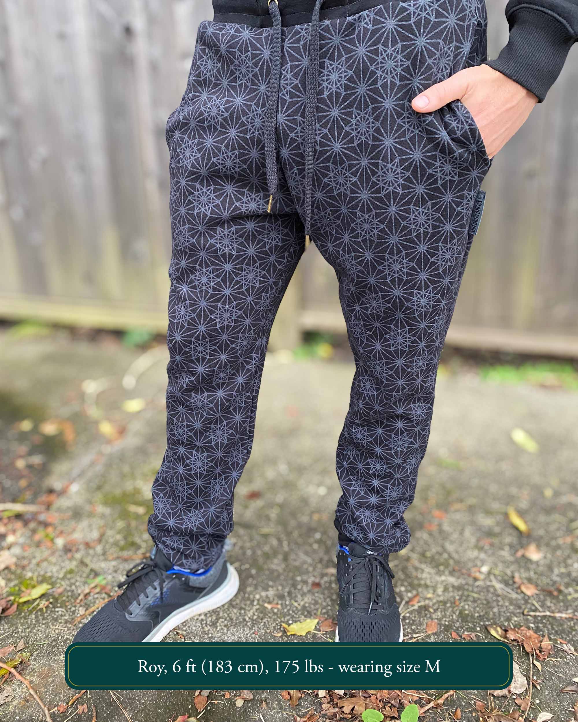 Organic cotton unisex joggers, black fabric with geometric print, front view on male model.