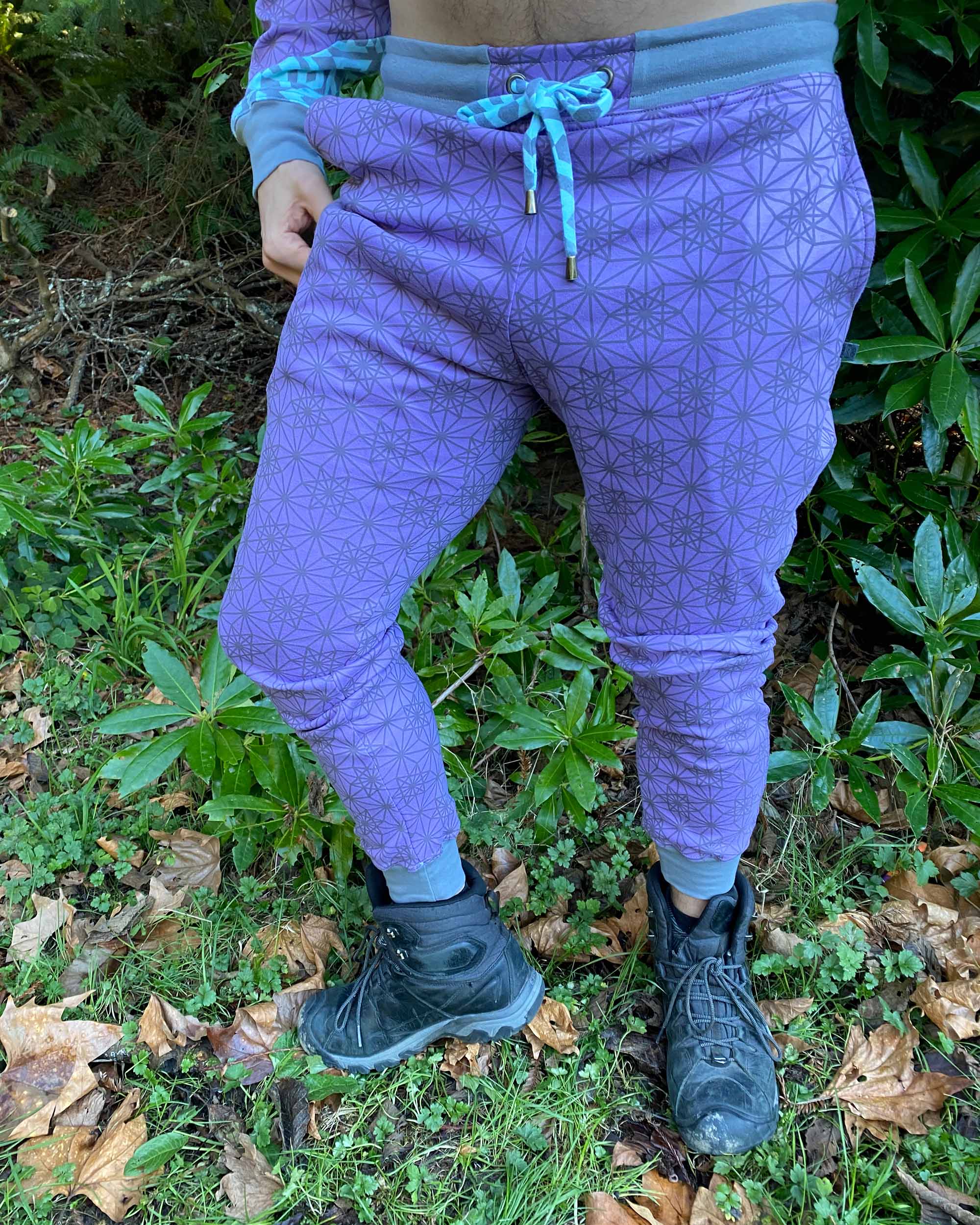 Organic cotton unisex joggers, lavender fabric with geometric print and blue accents, front view on male model.