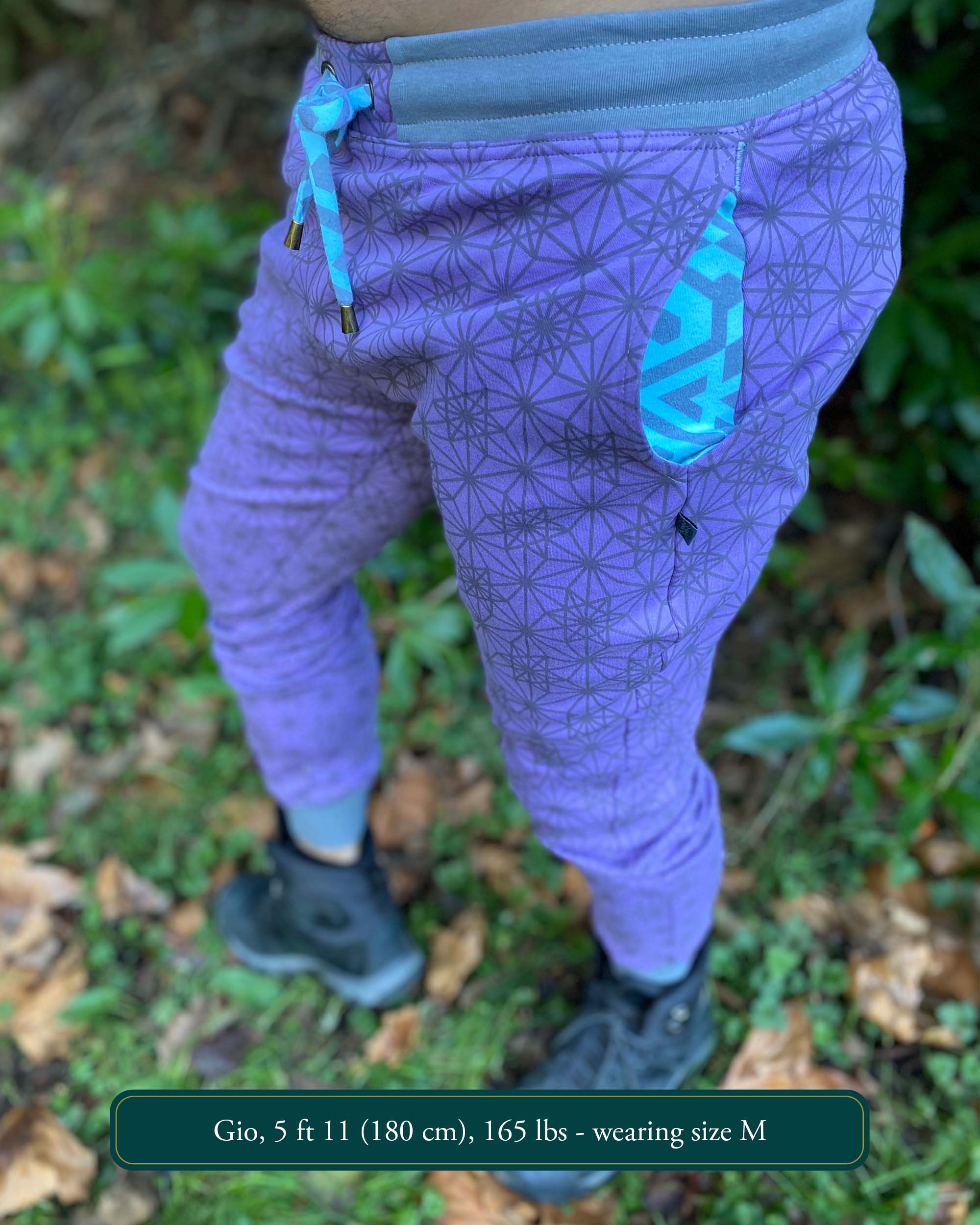 Organic cotton unisex joggers, lavender fabric with geometric print and blue accents, left side view on male model.