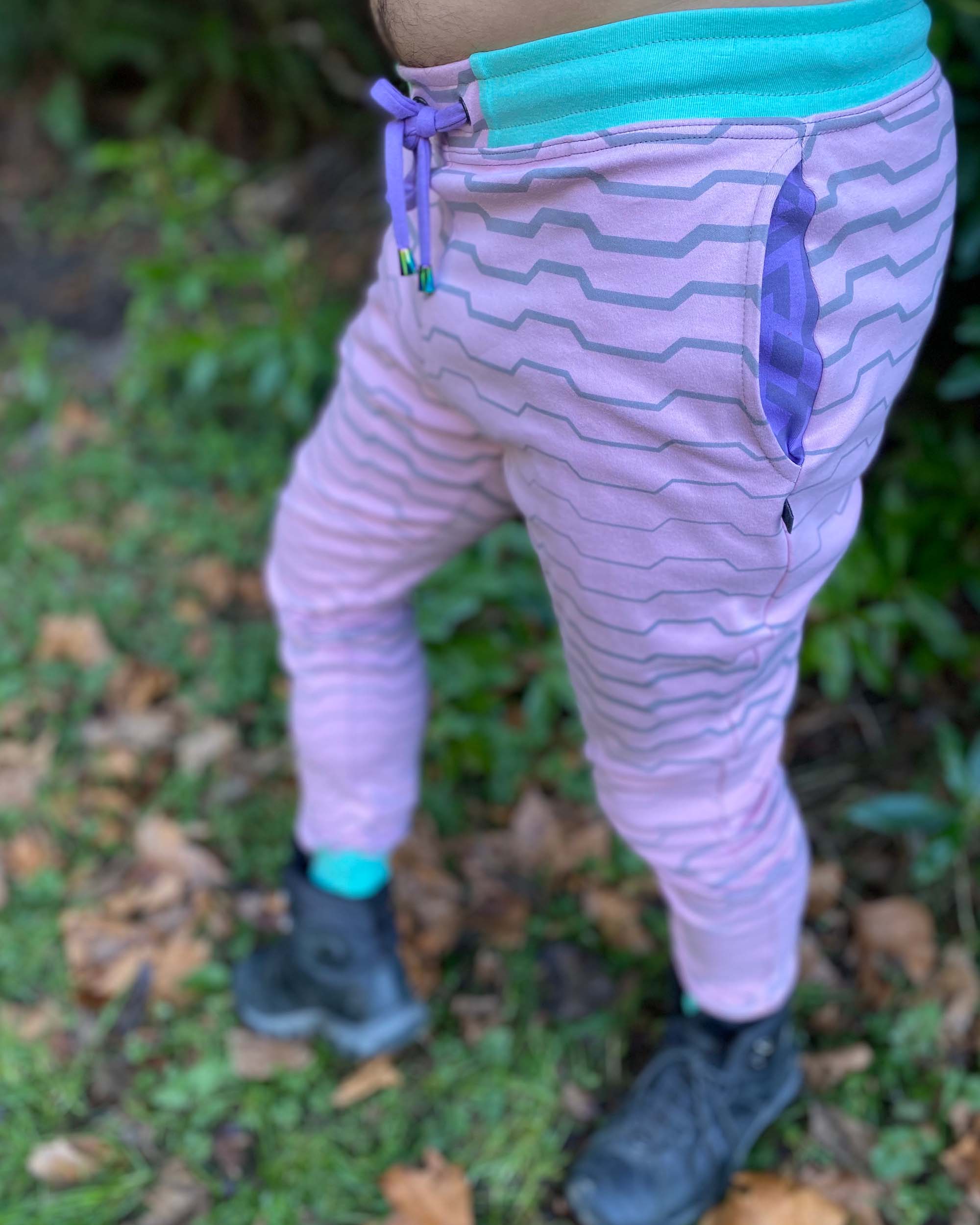 Organic cotton unisex joggers, pink fabric with grey geometric print, front left side view on male model.