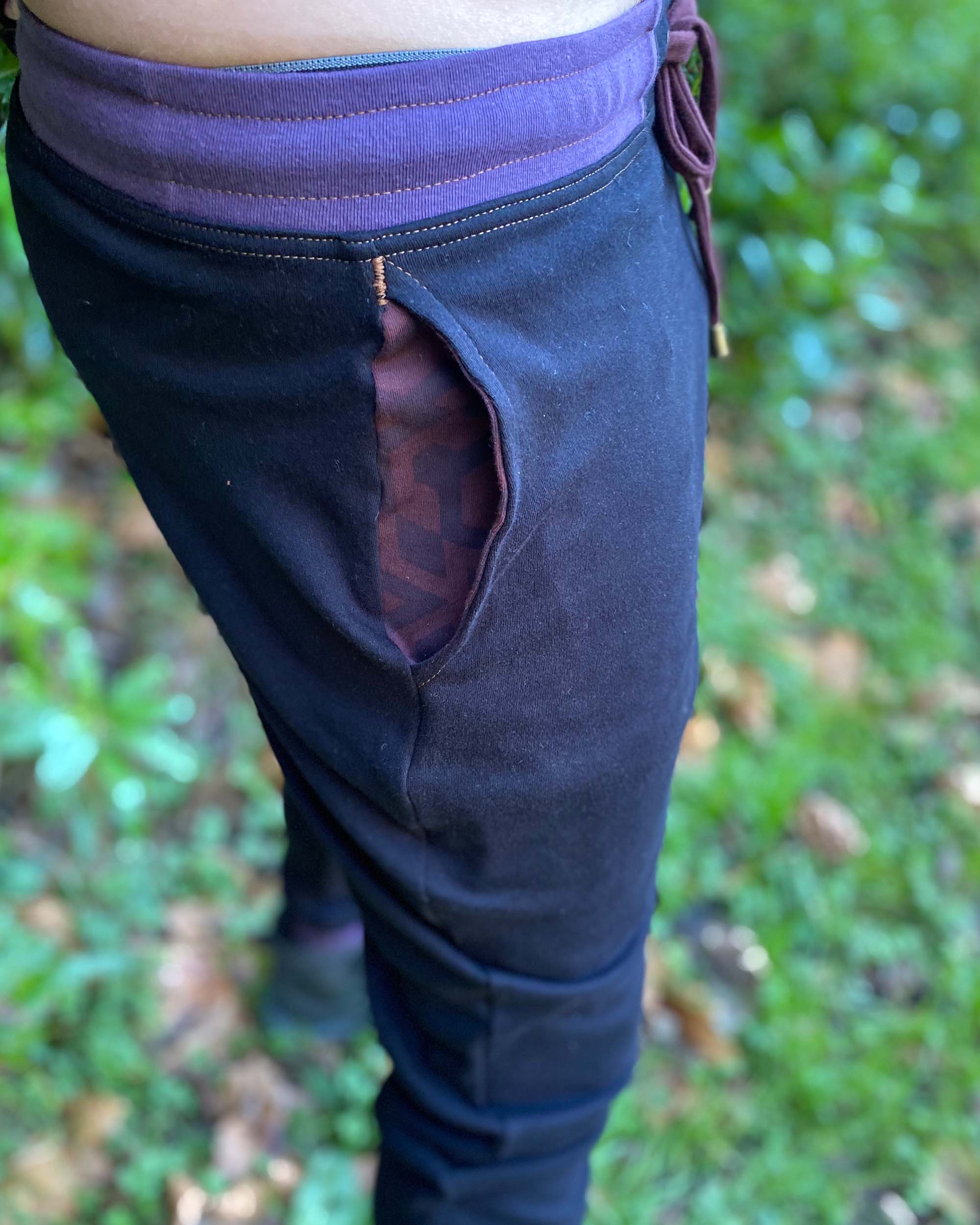 Organic cotton unisex joggers, black fabric with brown accents, detail view of pocket.