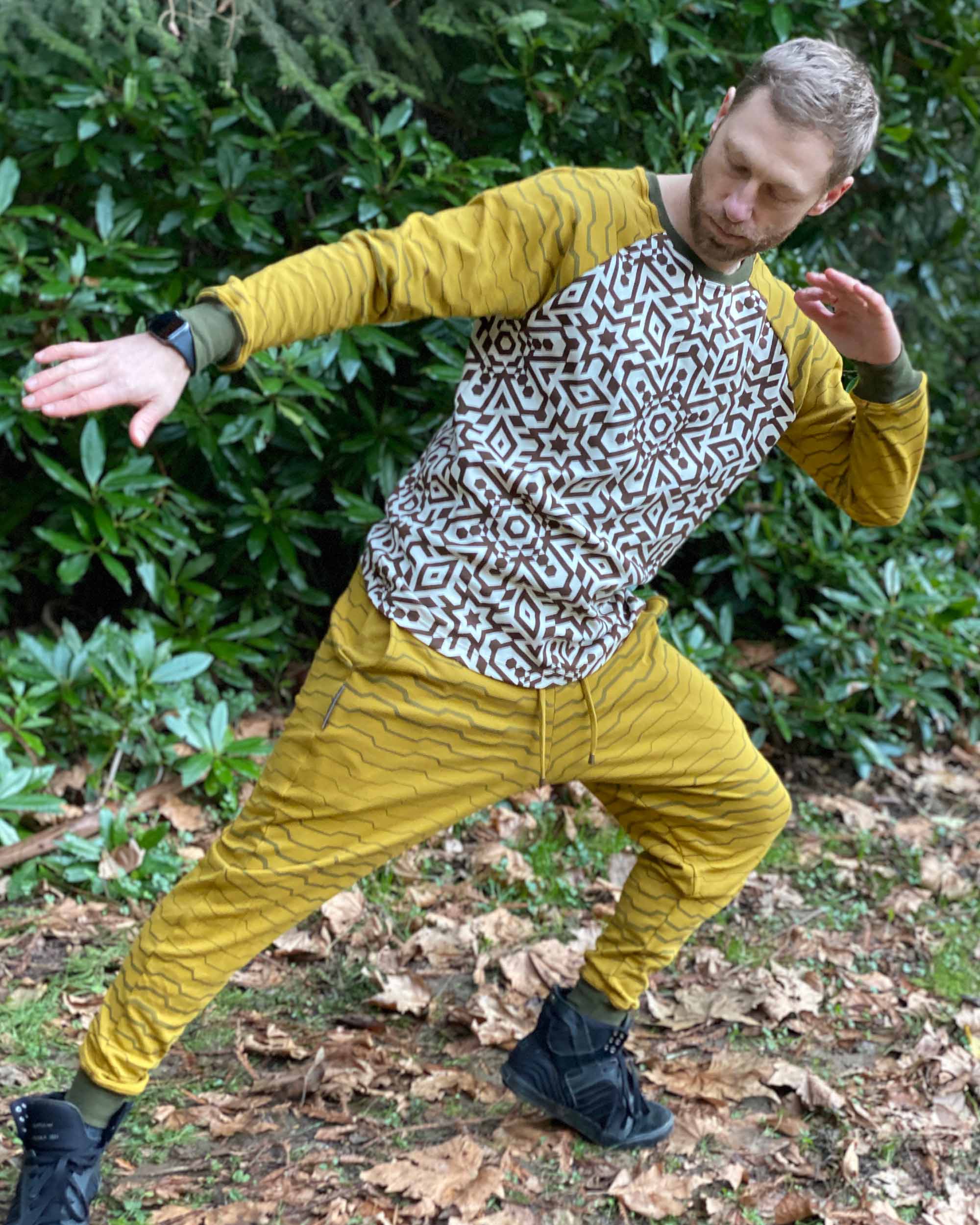 Full body view of male model wearing matching joggers and long sleeve shirt with yellow fabric and geometric print.
