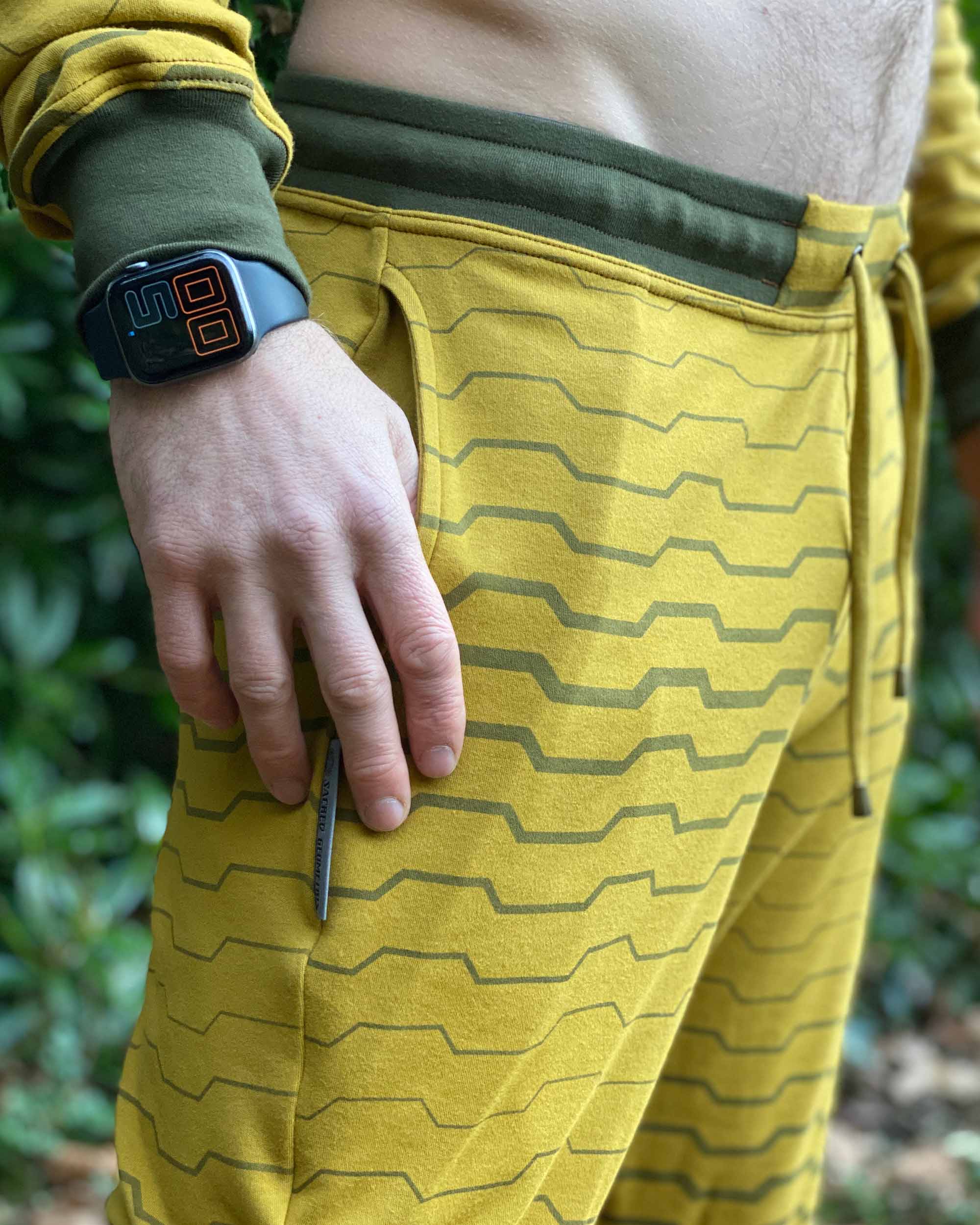 Organic cotton unisex joggers, yellow fabric with geometric print, front right side detail view.