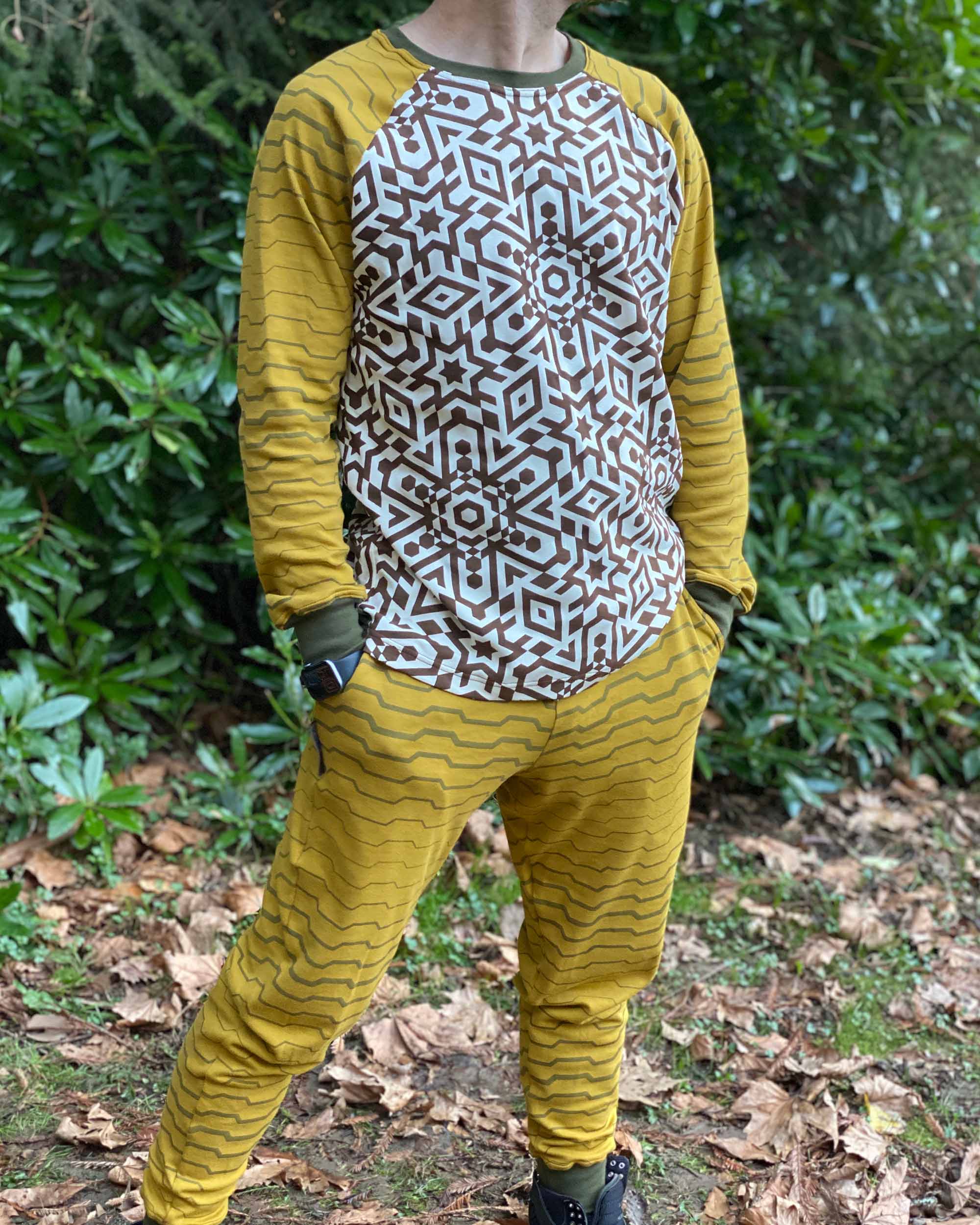 Full body view of male model wearing organic cotton unisex joggers and matching long sleeve shirt with geometric print.