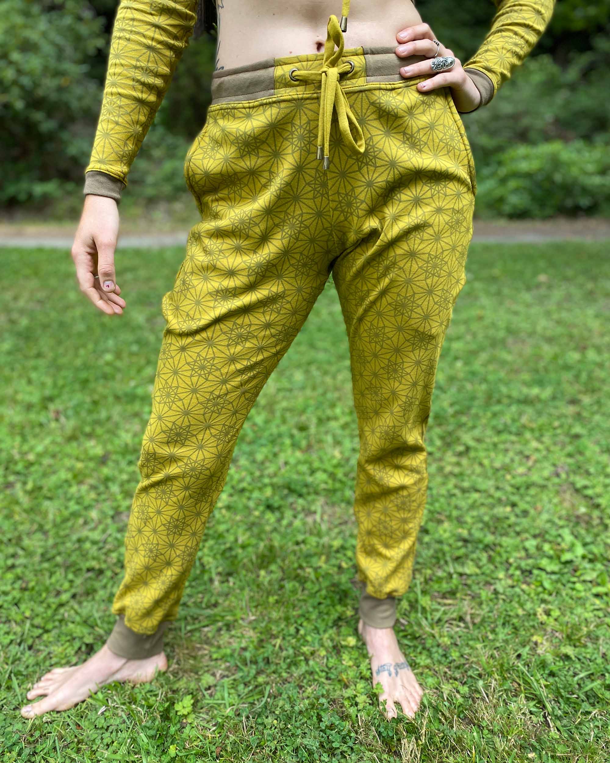 Organic cotton unisex joggers, yellow fabric with geometric print, left side view on female model.