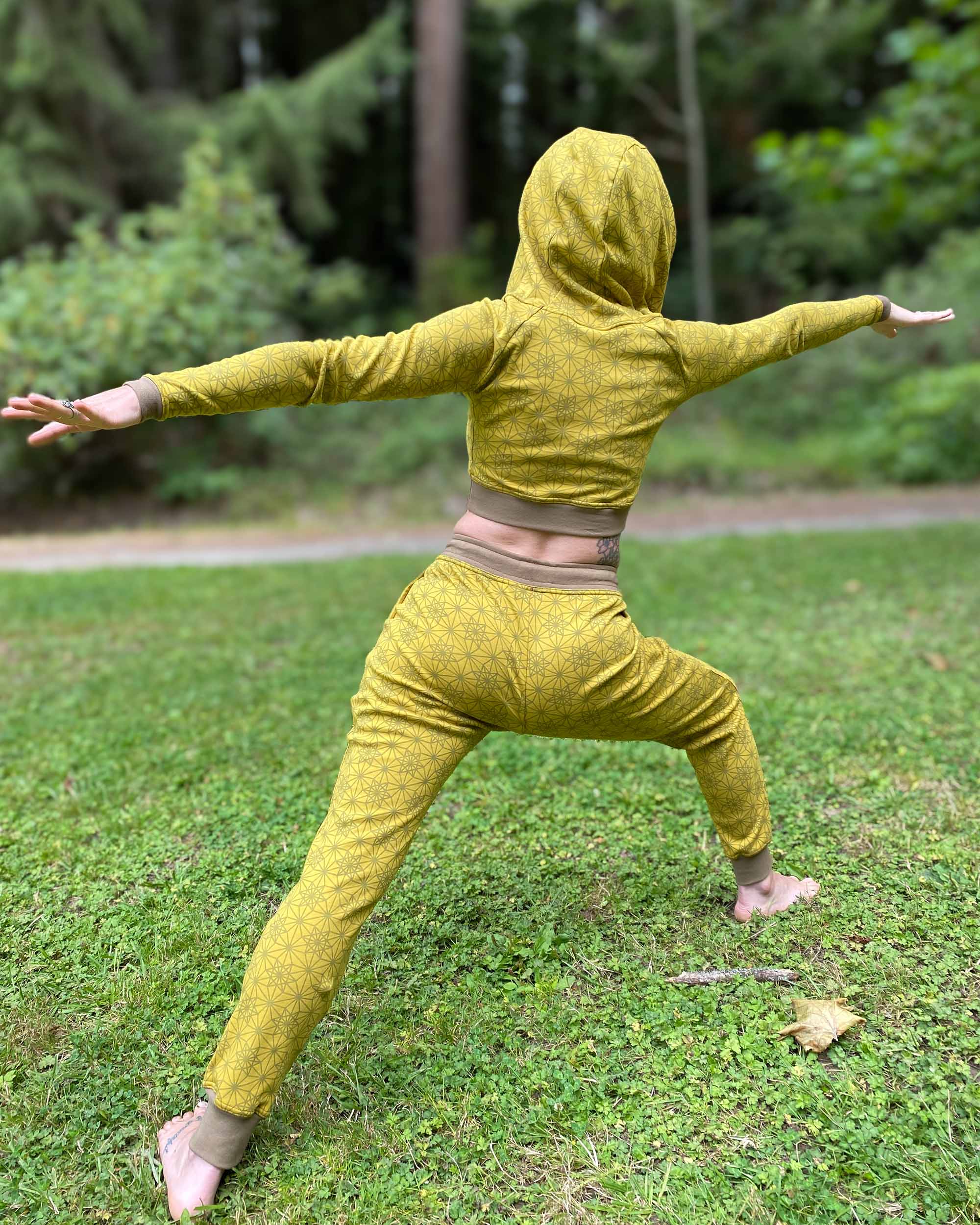 Organic cotton unisex joggers, yellow fabric with geometric print, back view on female model doing yoga.