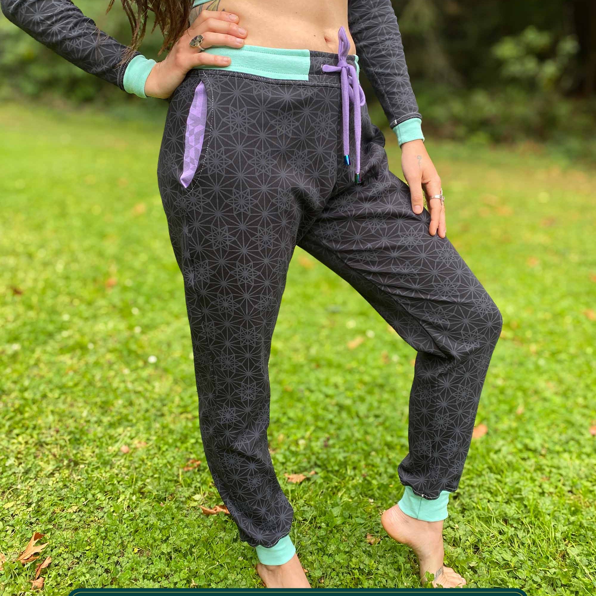 Organic cotton unisex joggers, black fabric with geometric print and purple accents, front view on female.