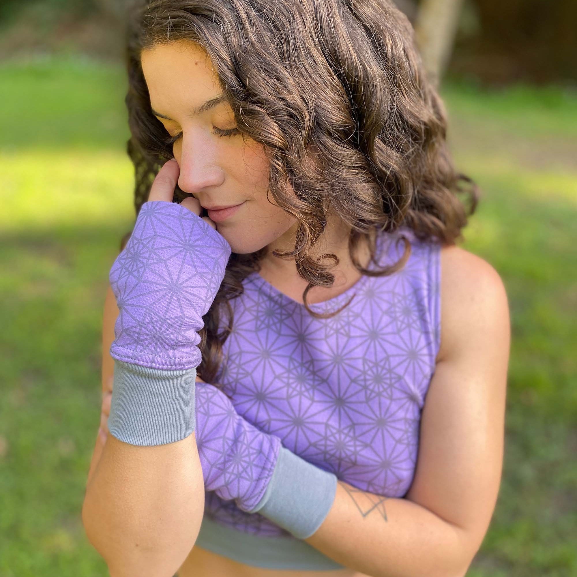 Organic cotton hand warmers, lavender fabric with geometric print, front view with female model.