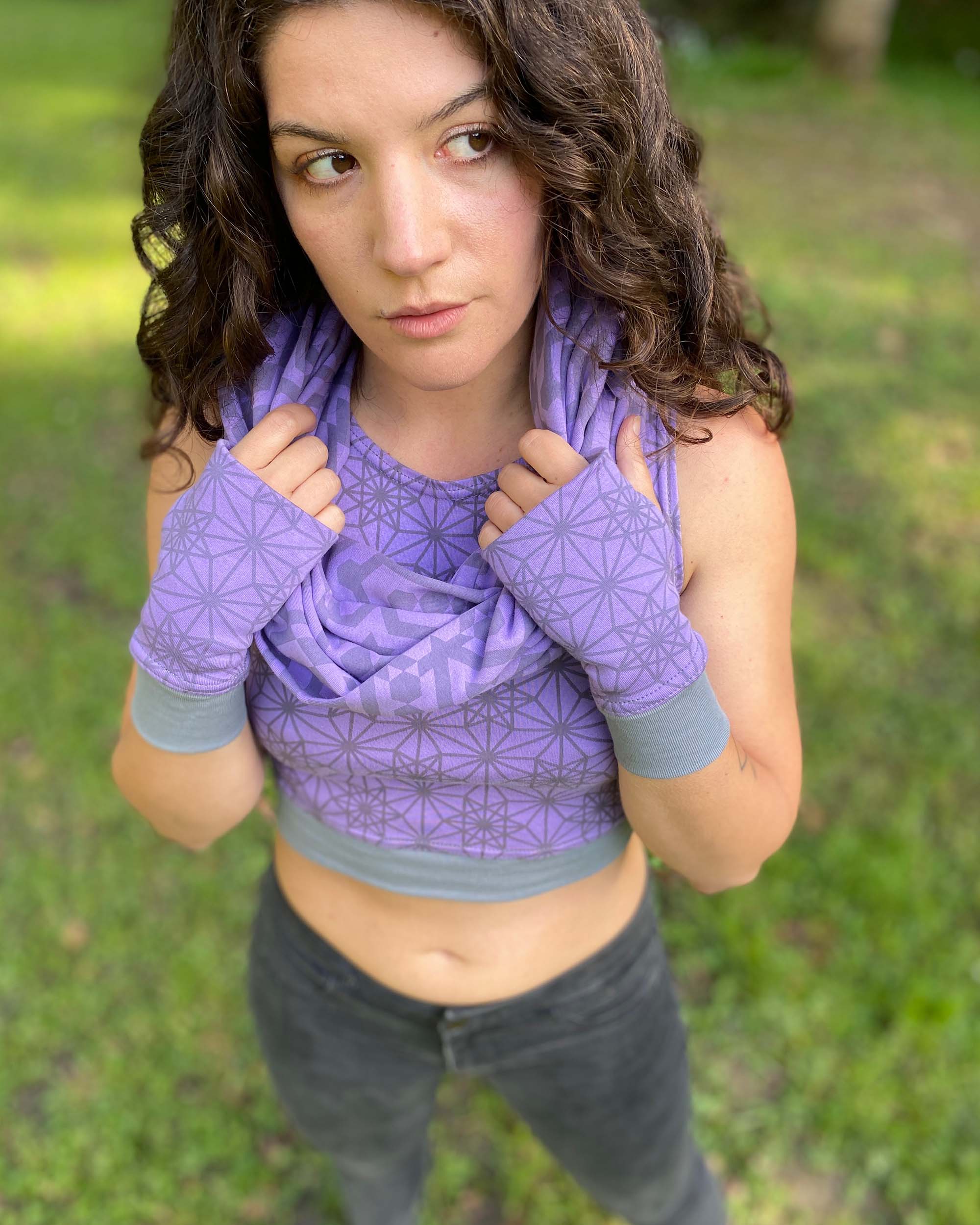 Organic cotton hand warmers, lavender fabric with geometric print, front view with female model wearing matching scarf.