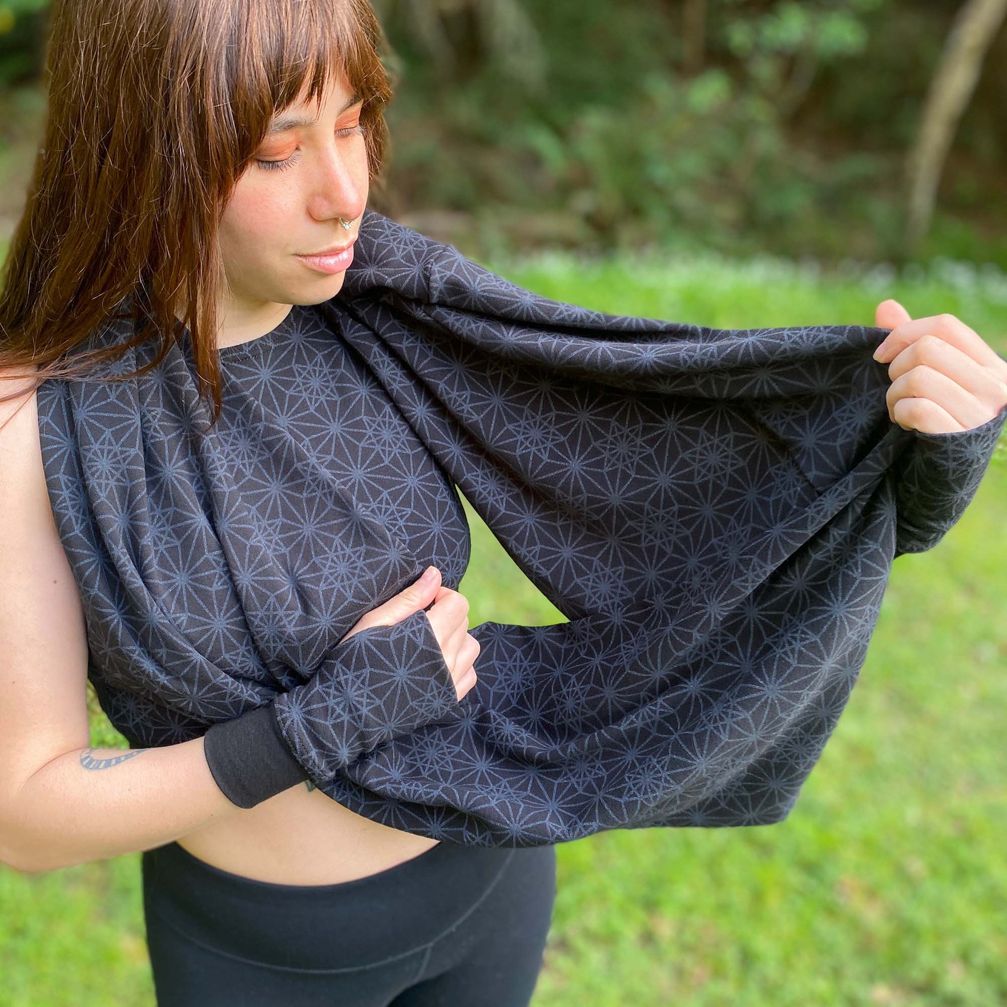 Organic cotton infinity scarf, black fabric with sacred geometry print, front side view on female model.