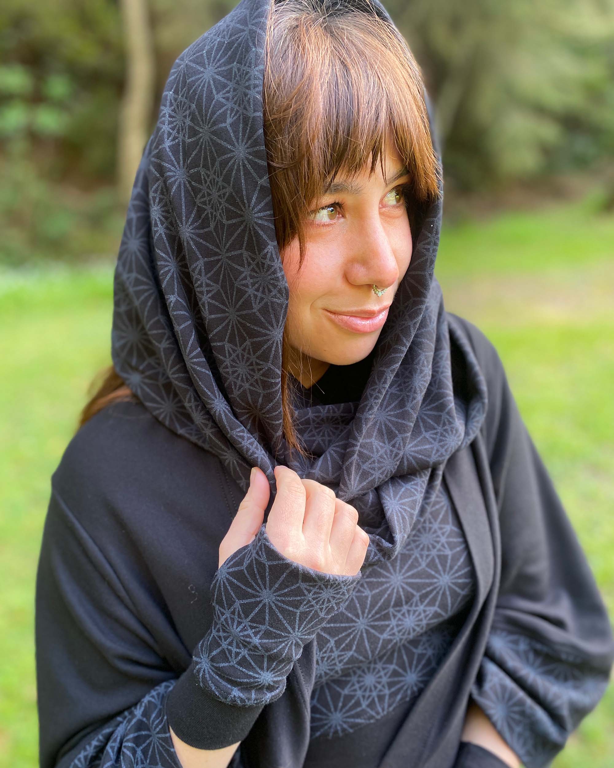 Organic cotton infinity scarf, black fabric with sacred geometry print, worn as head wrap on female model.