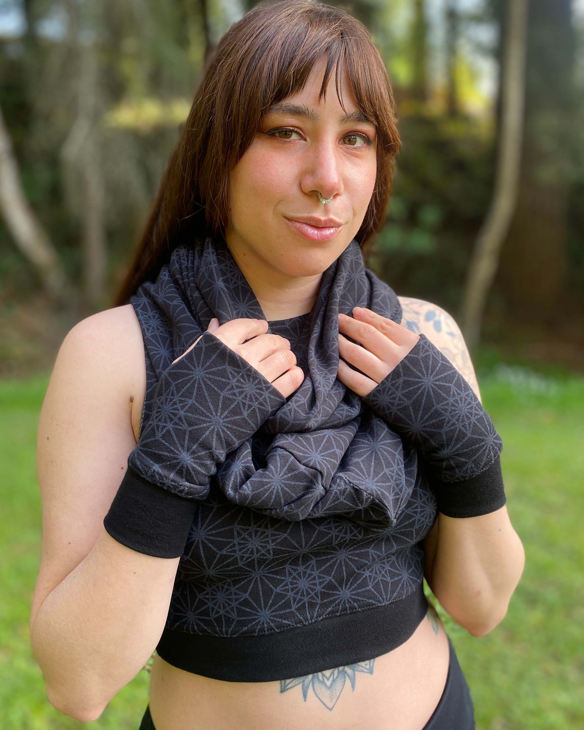 Organic cotton infinity scarf, black fabric with sacred geometry print, front view worn by female model.