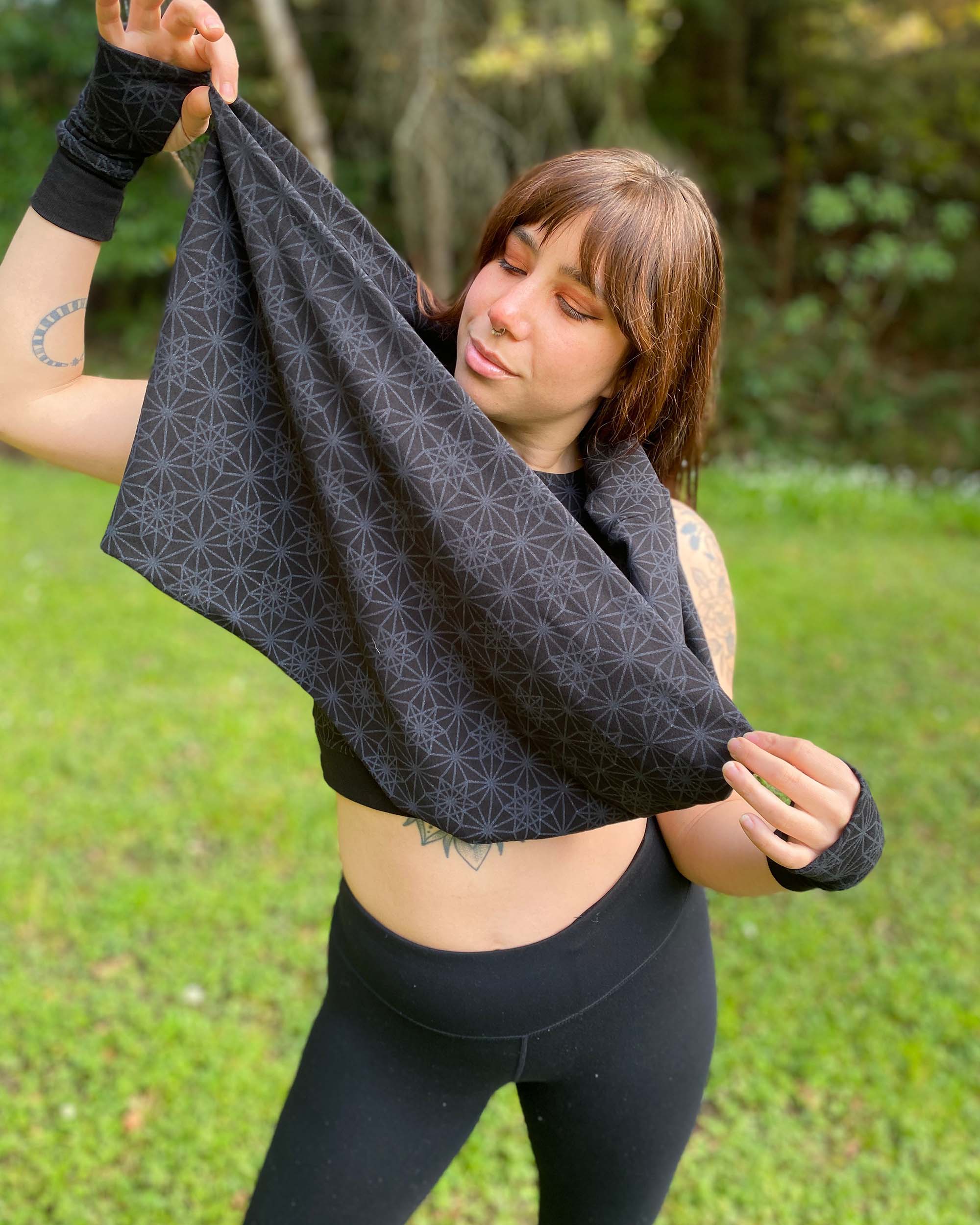 Organic cotton infinity scarf, black with screen printed sacred geometry fabric, front view on female model.