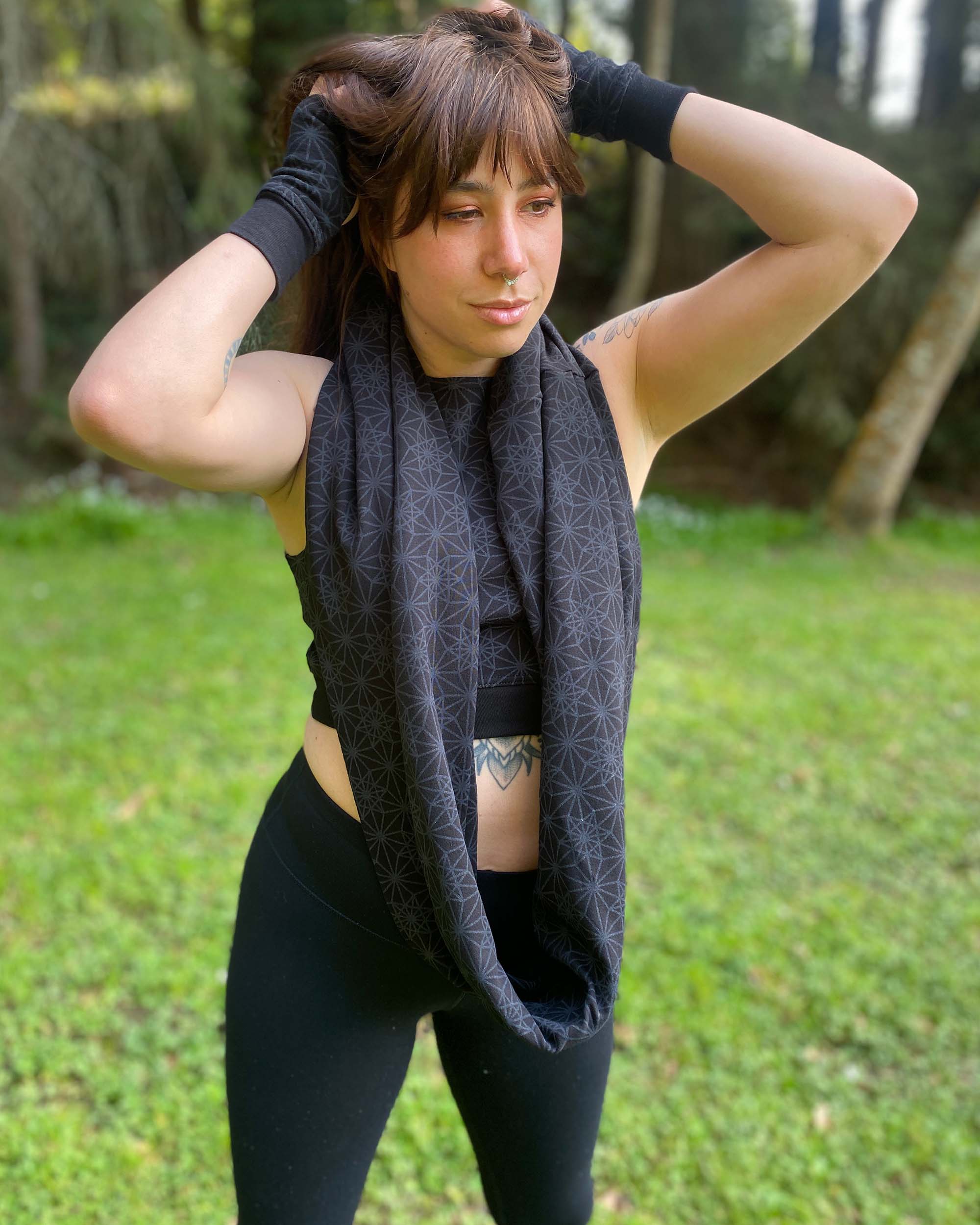 Organic cotton infinity scarf, black fabric with geometric print, front view worn by female model.