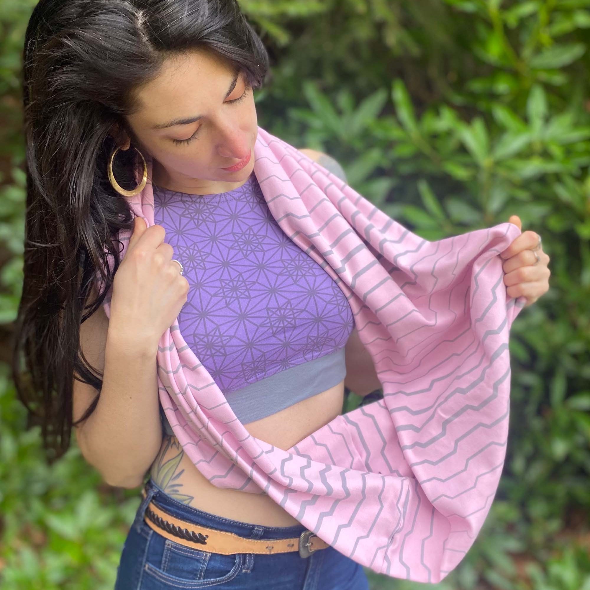 Organic cotton infinity scarf, pink fabric with geometric stripes, front right side view on female model.
