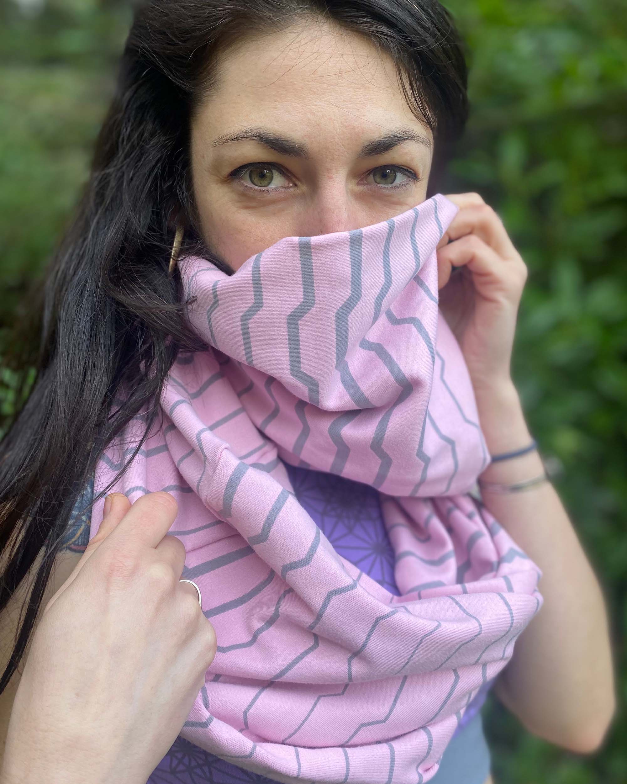 Organic cotton infinity scarf, pink fabric with geometric stripes, front detail view on female model.