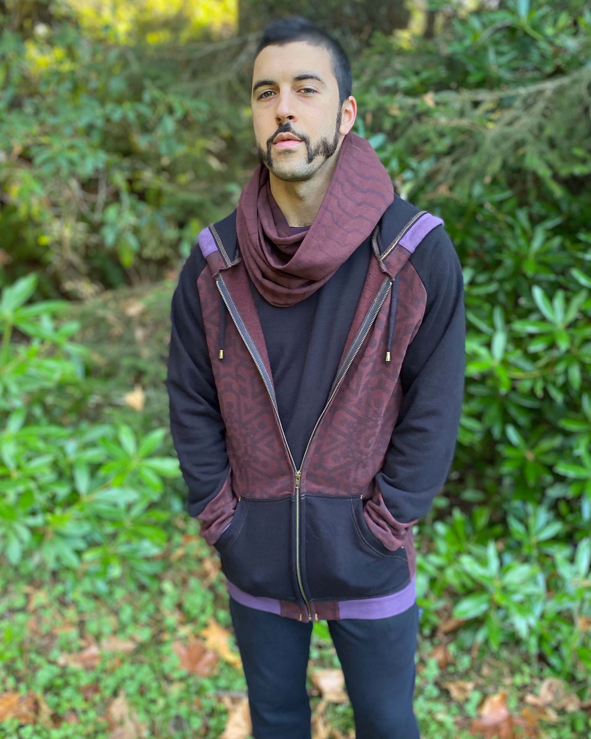Organic cotton infinity scarf, brown fabric with geometric stripes, front view on male model in matching hoodie.