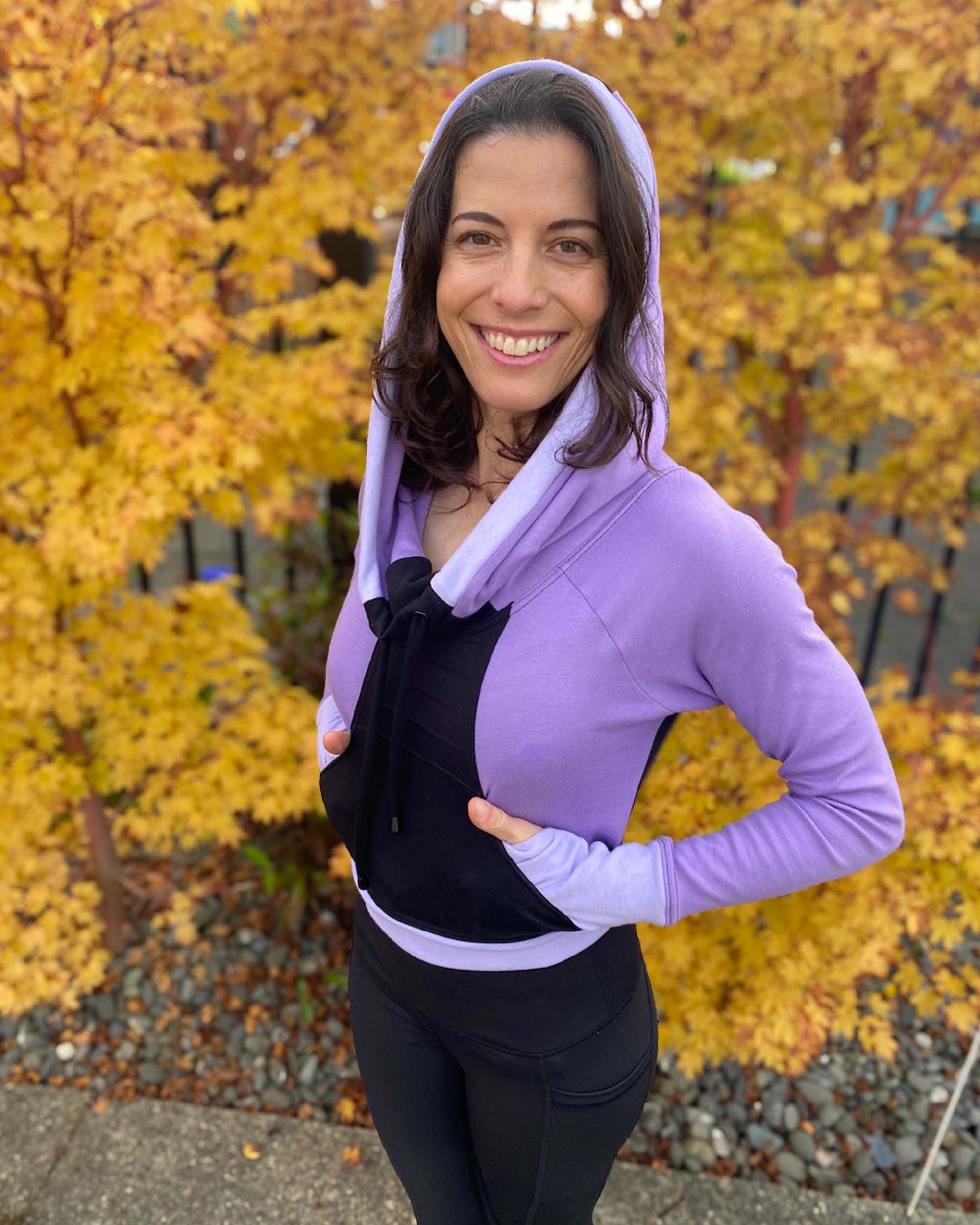 Fitted crop hoodie with cowl hood, black fabric with lavender accent, front view on model.