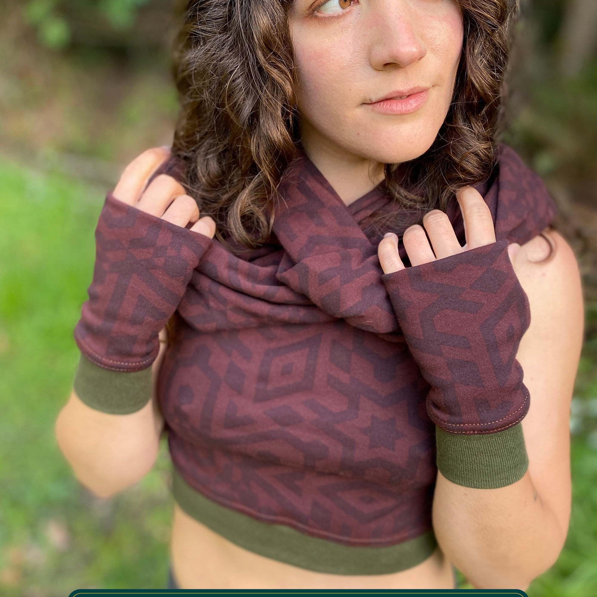 Female model wearing matching set of crop top, infinity scarf and fingerless gloves, brown organic cotton fabric with geometric print, front view.