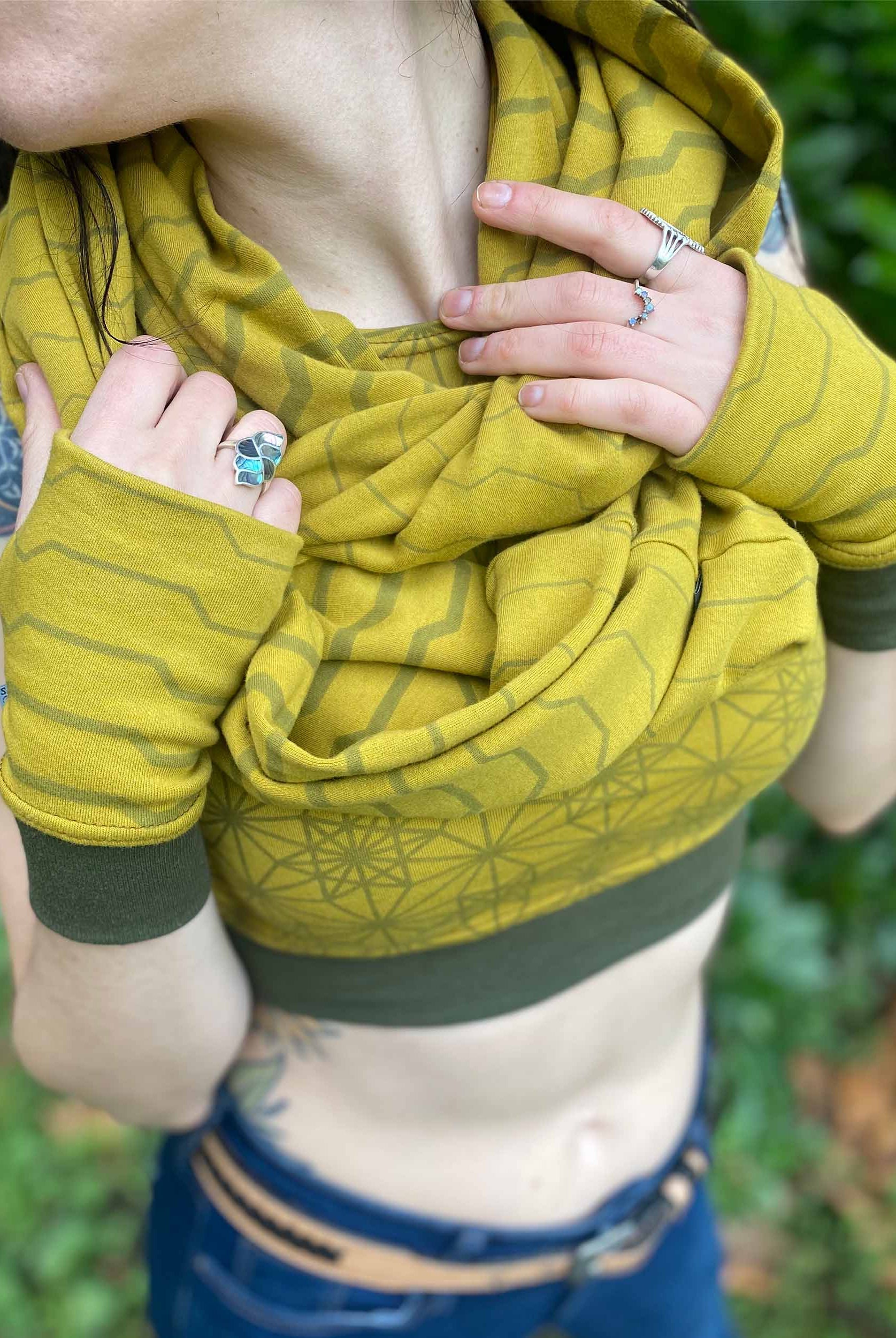 Female model wearing matching set of crop top, infinity scarf and fingerless gloves, yellow organic cotton fabric with stripes, detail view.