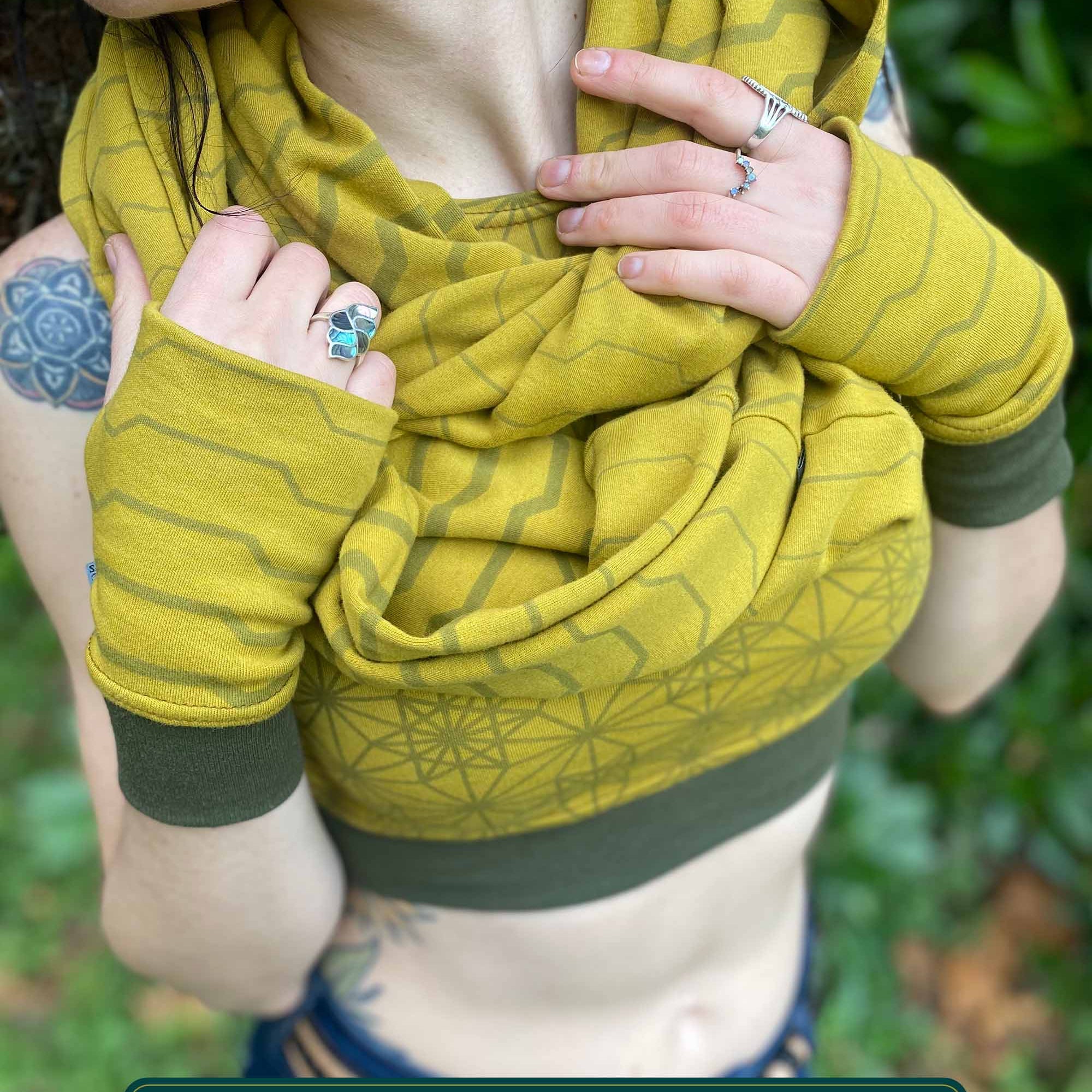 Female model wearing matching set of crop top, infinity scarf and fingerless gloves, yellow organic cotton fabric with geometric stripes, detail view.