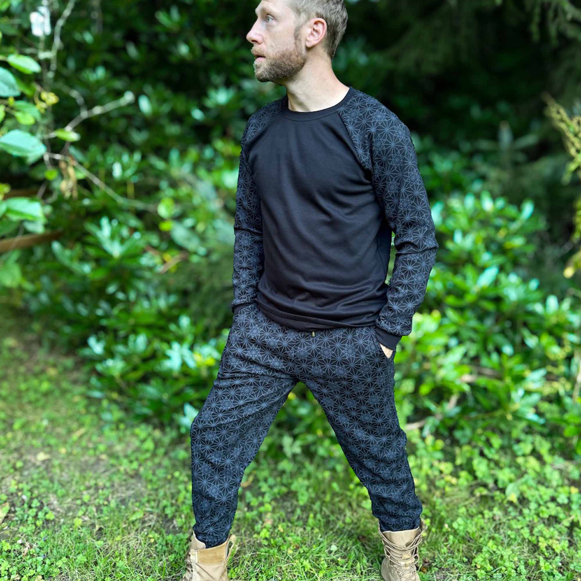 Men's matching joggers and long sleeve shirt, black with geometric printed accent fabric, worn by male model in nature.