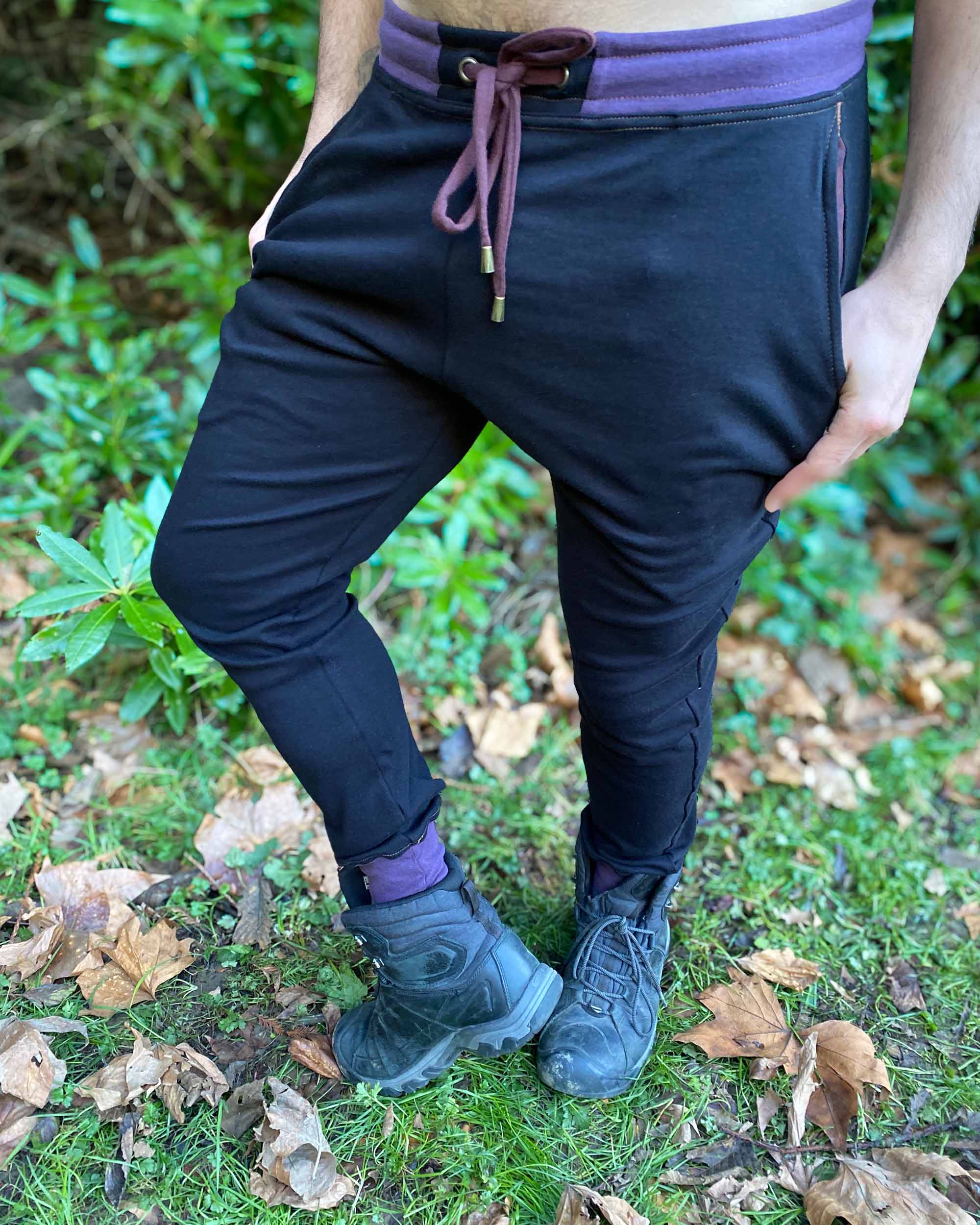 Organic cotton knit joggers, black with brown and purple accents, front view on male model.