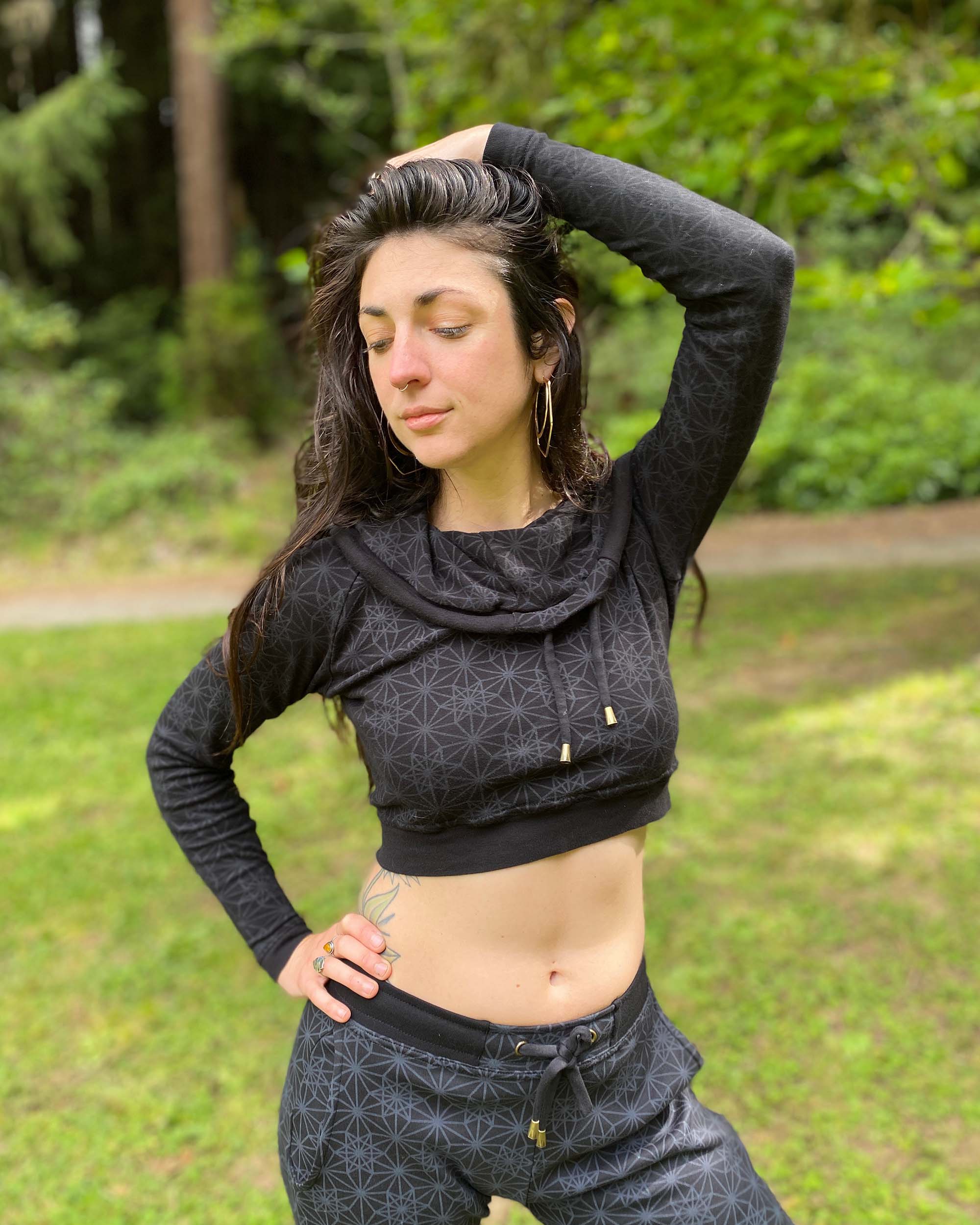 Women's matching two piece set, joggers and crop hoodie, black fabric with geometric print, front view on model.