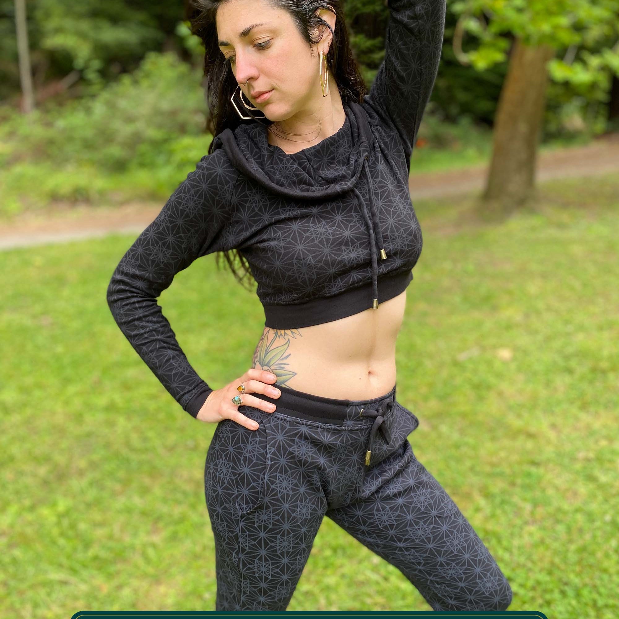 Women's matching two piece outfit, joggers and crop hoodie, black fabric with geometric print, front view on model.