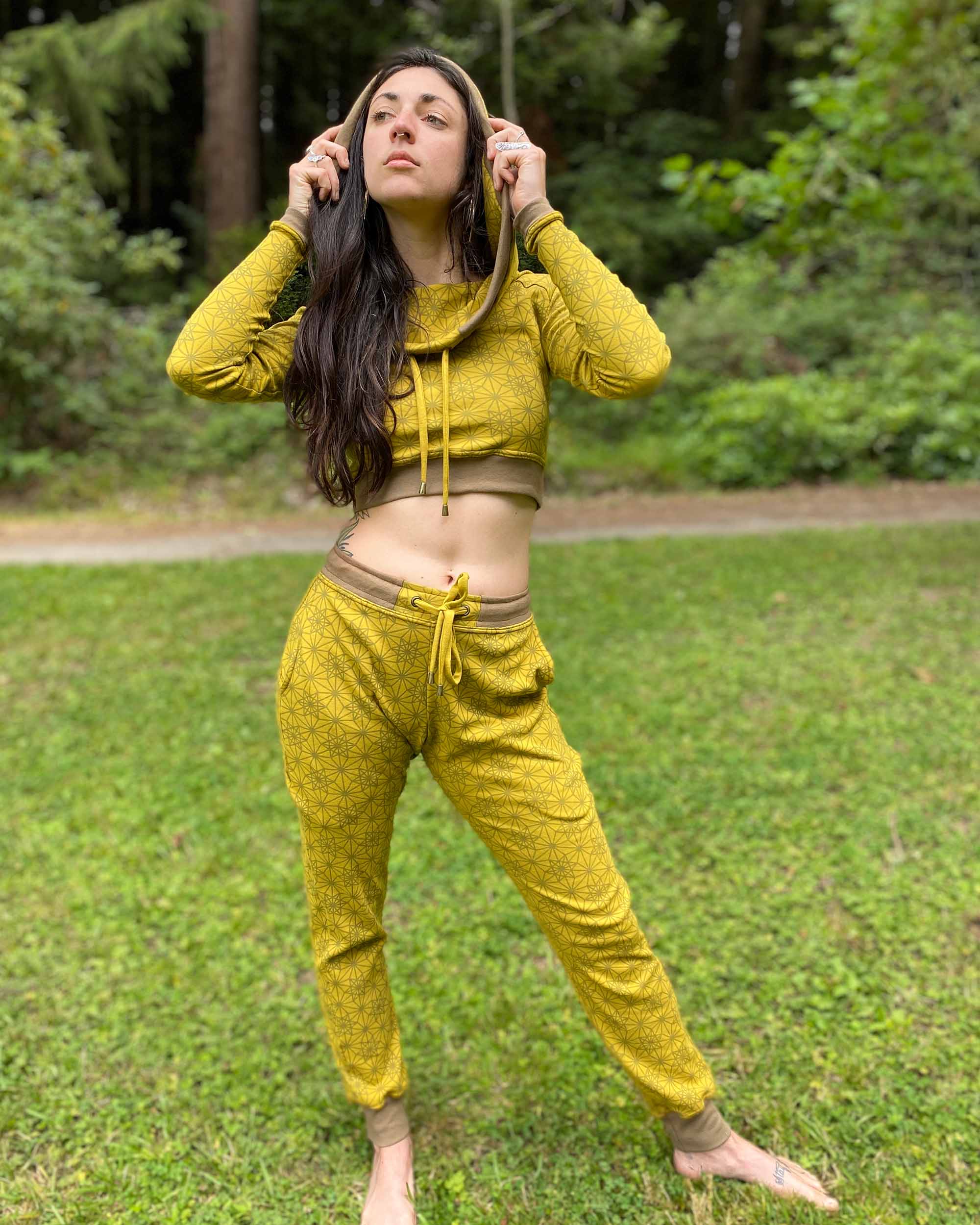 Women's matching two piece outfit, joggers and crop hoodie, yellow fabric with geometric print, front view worn with hood on.