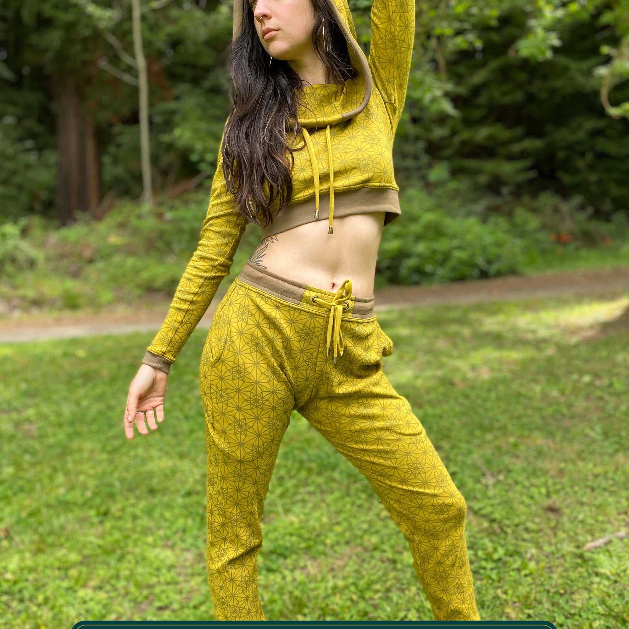 Women's matching two piece outfit, joggers and crop hoodie, yellow with geometric printed fabric, full length view on model.
