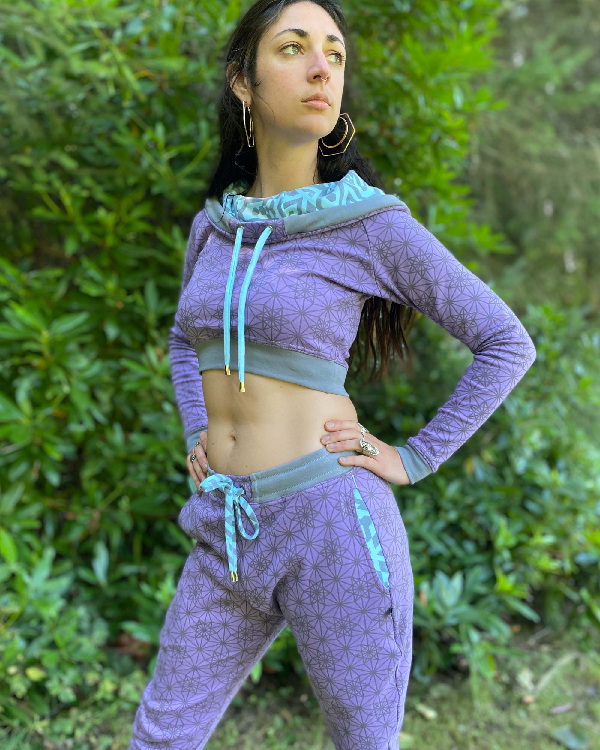 Matching two piece set, joggers and crop hoodie, lavender with geometric printed fabric, left side view on female model.