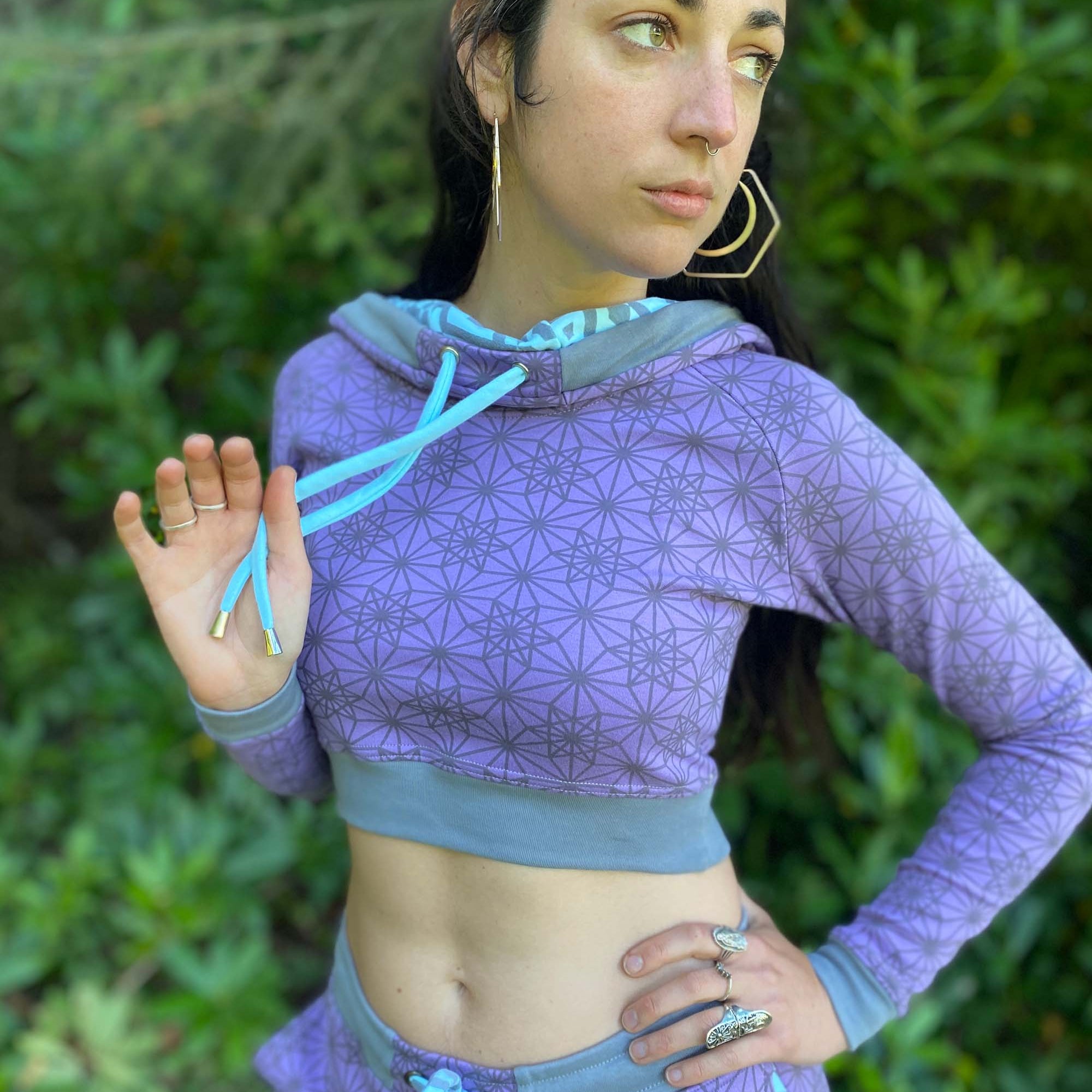 Matching two piece set, joggers and crop hoodie, lavender with geometric printed fabric, view from waist up on female model.