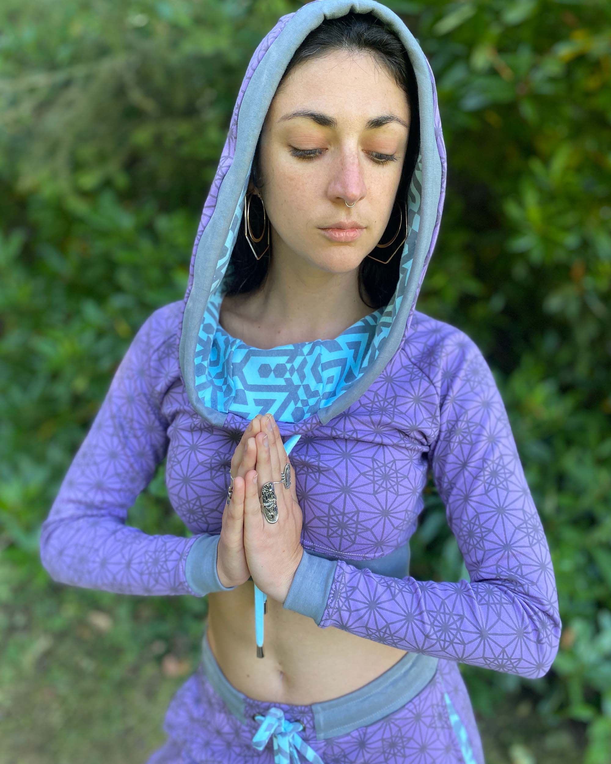 Matching two piece set, joggers and crop hoodie, lavender with geometric printed fabric, front view with hood worn.