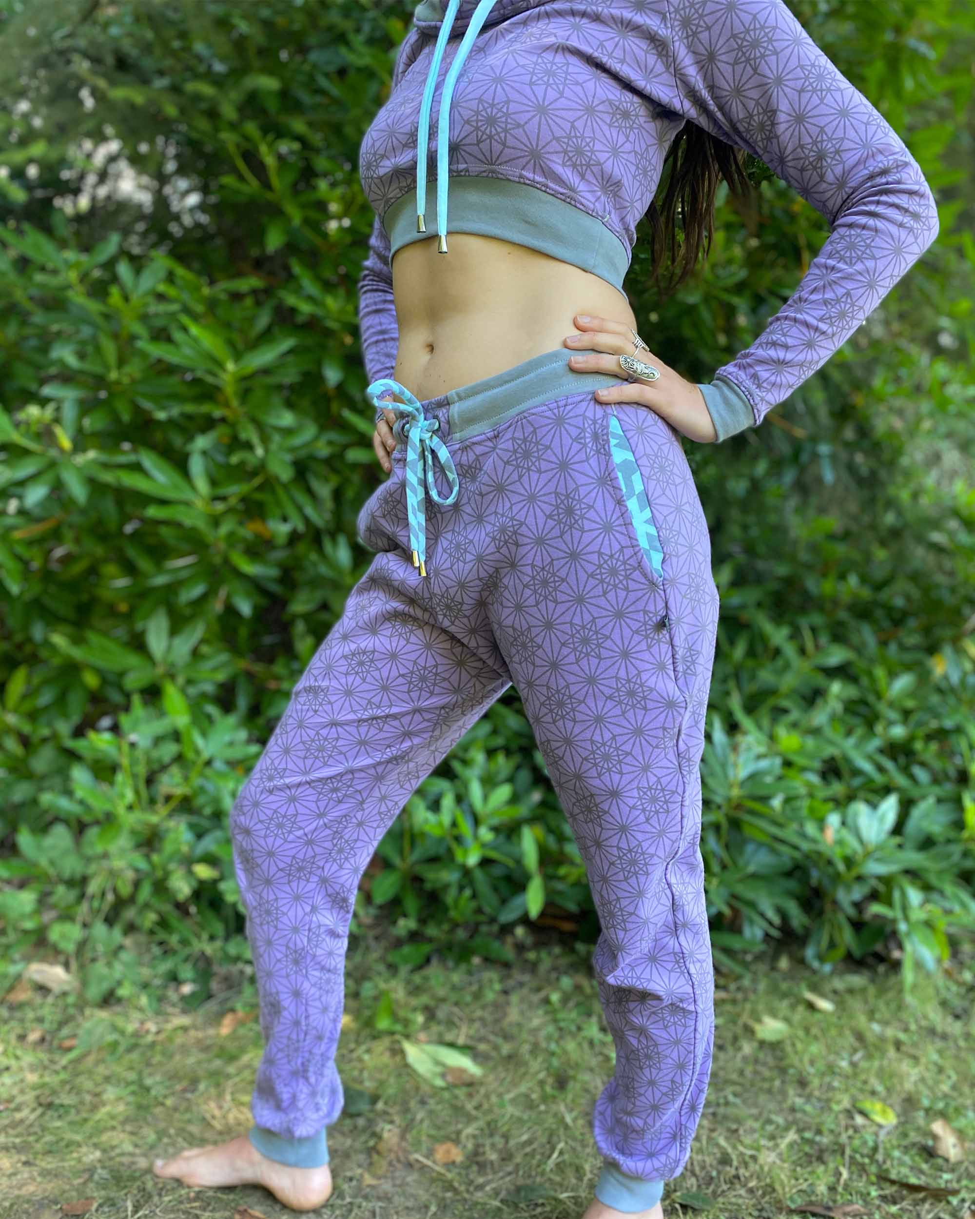Matching two piece set, joggers and crop hoodie, lavender with sacred geometry fabric, side view on female model.