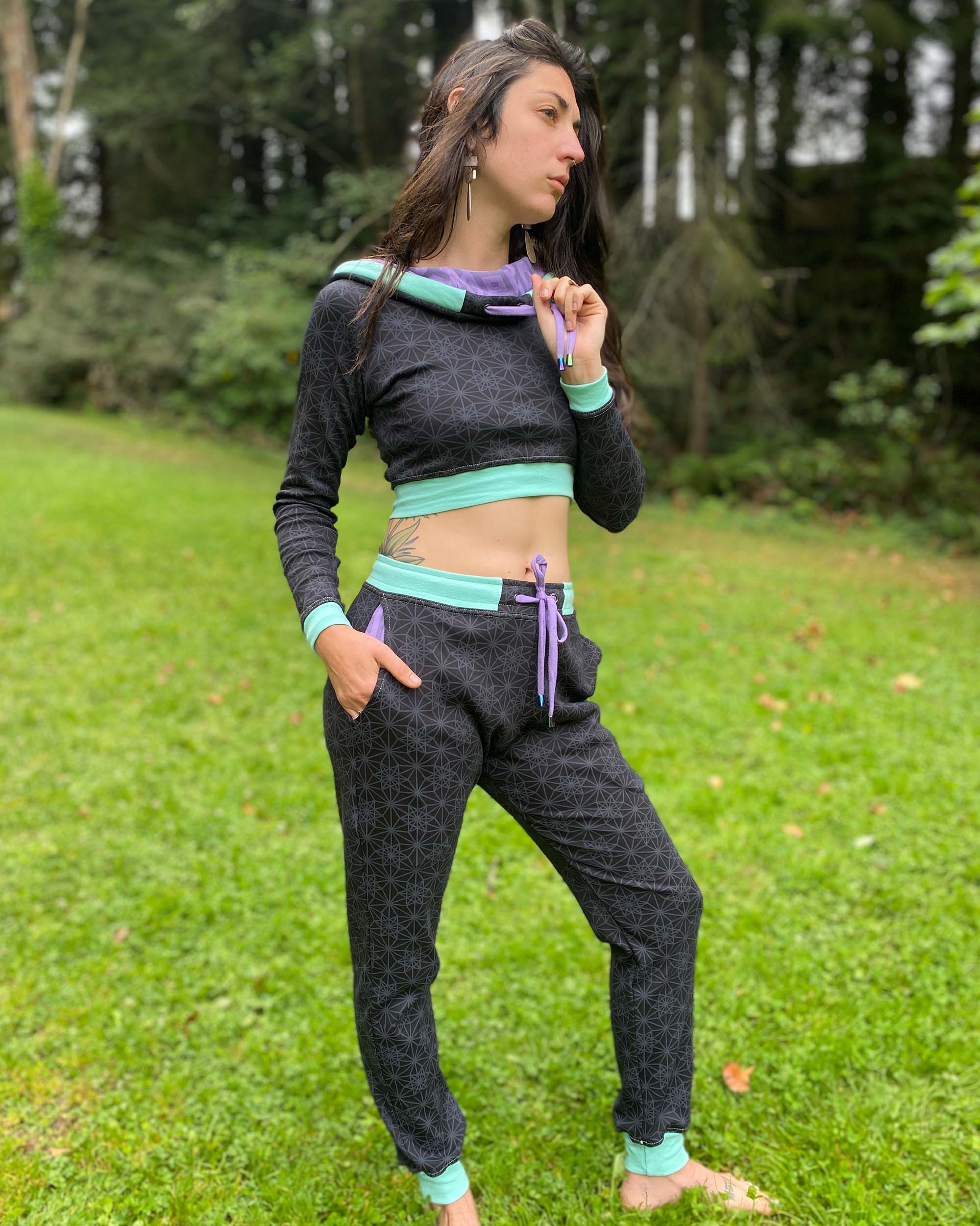 Women's matching two piece set, joggers and crop hoodie, black fabric with lavender geometric accents, full body
view.