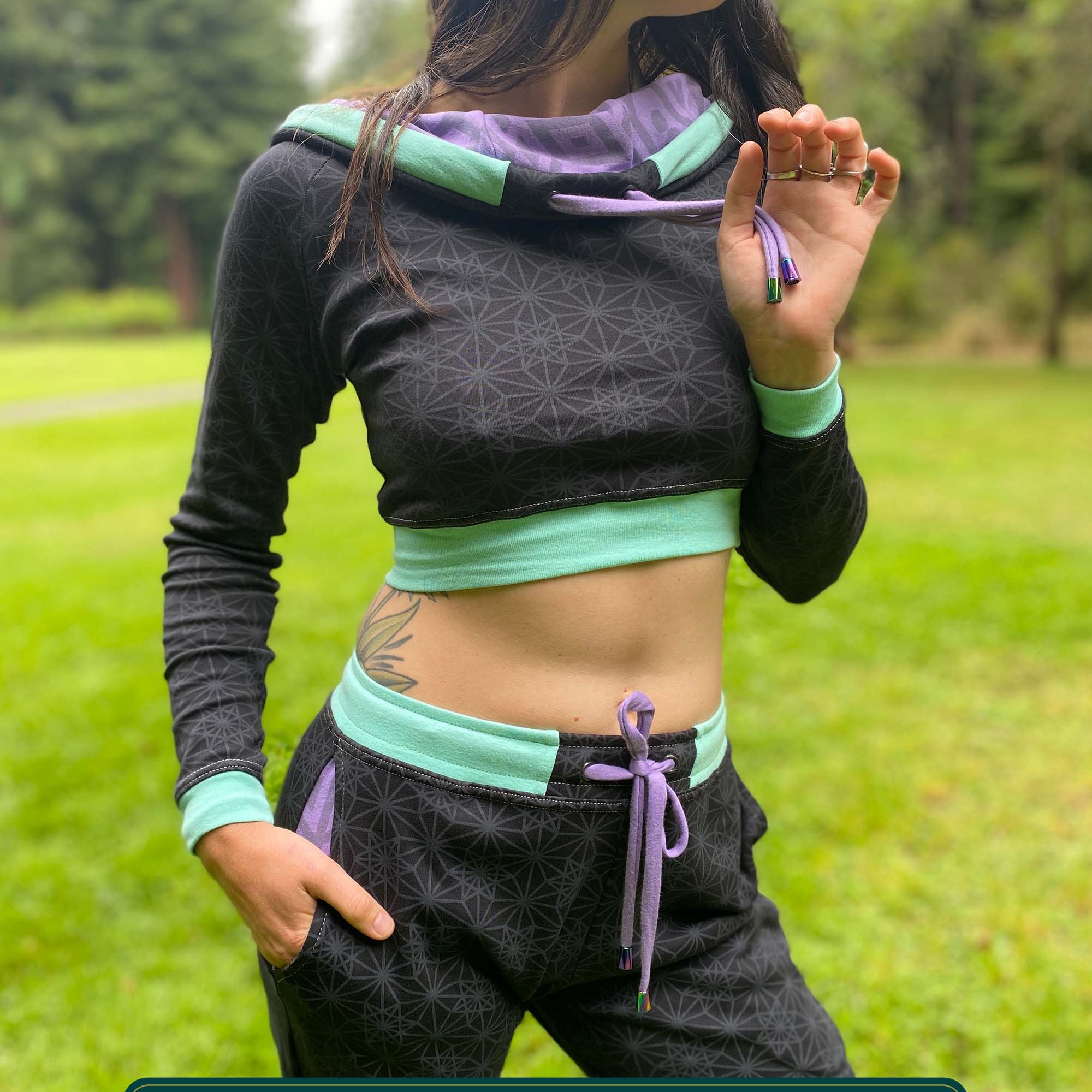 Women's matching two piece set, joggers and crop hoodie, black fabric with lavender accents, front view on model.