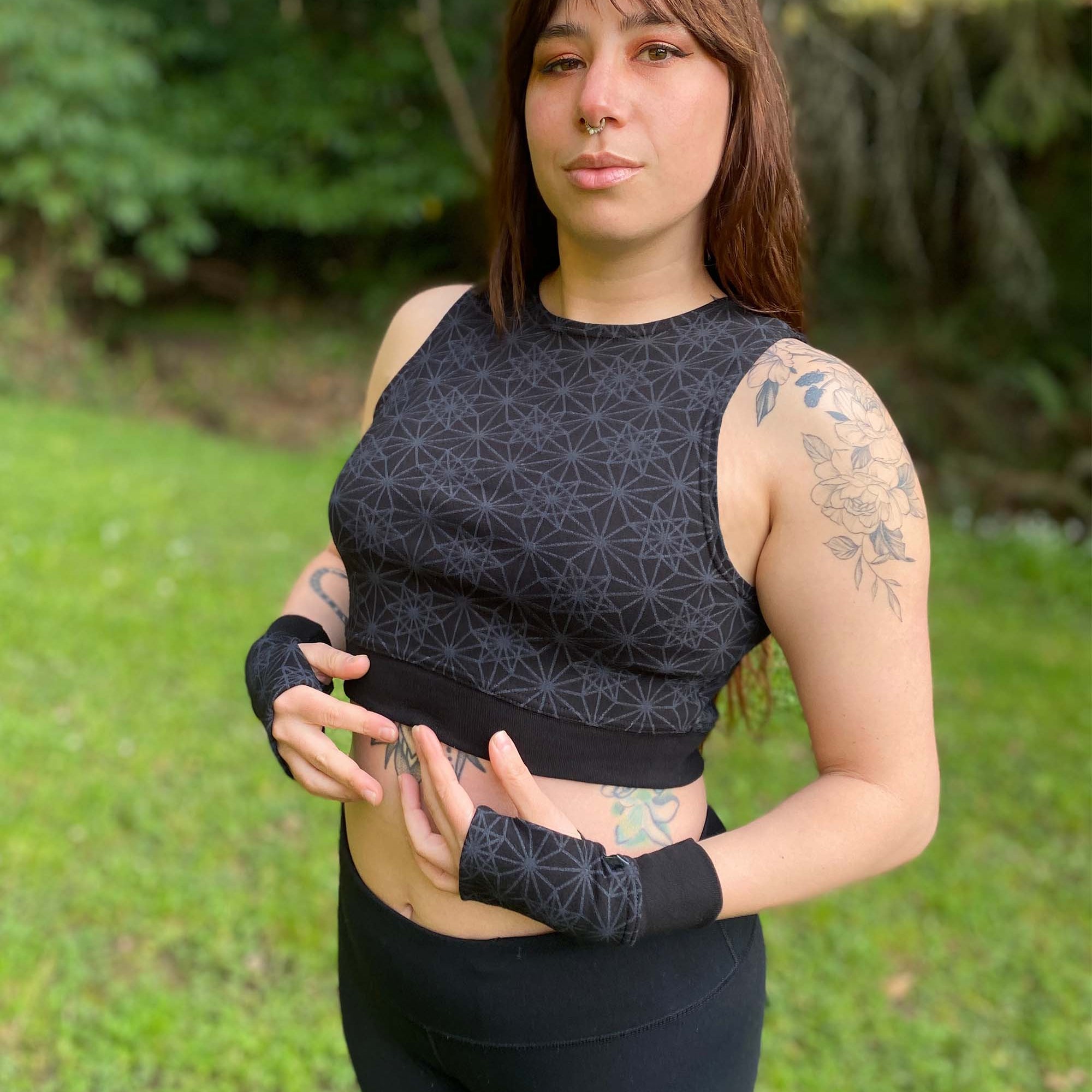 Organic cotton crop top, black fabric with sacred geometry print, front left side view on female model.